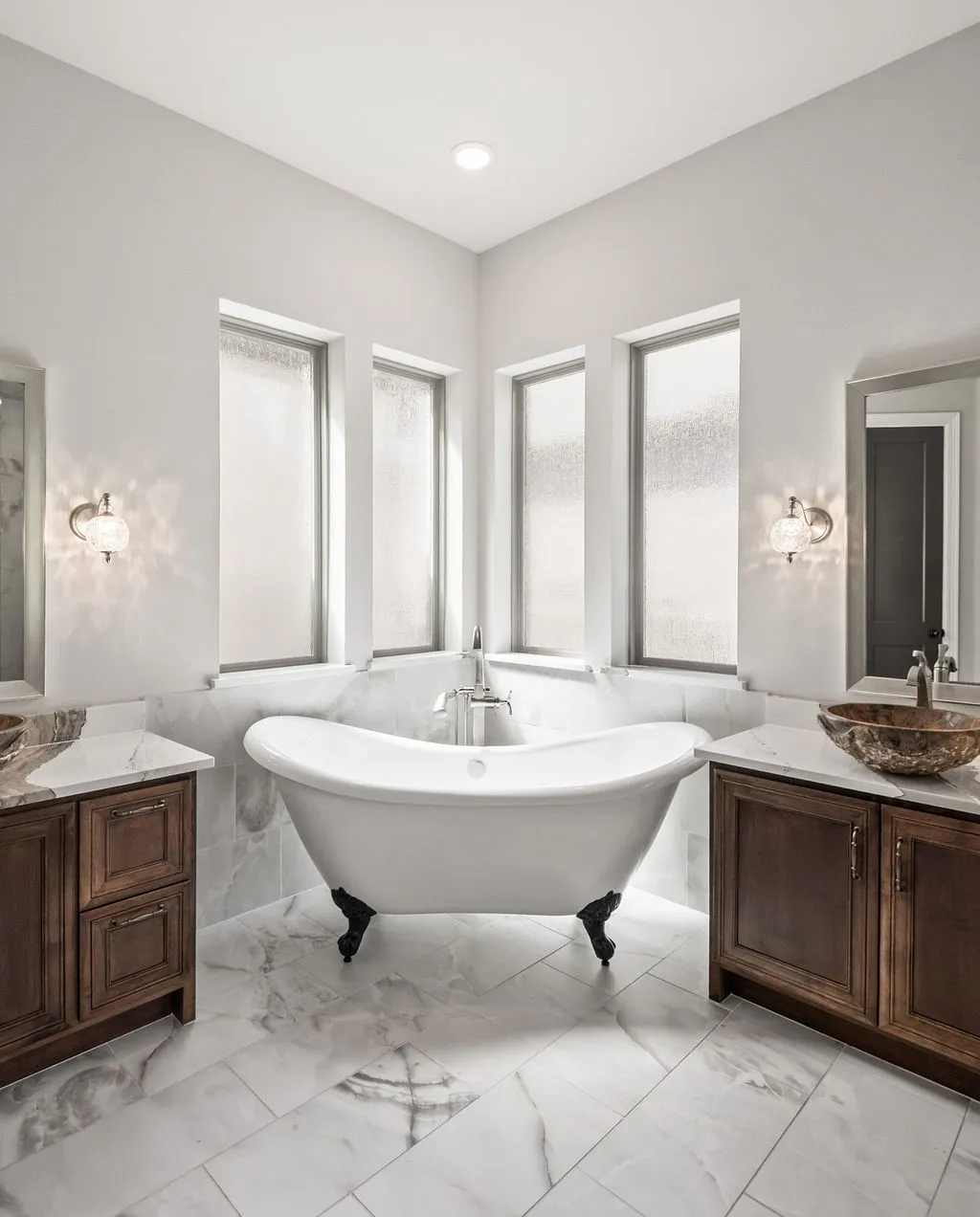 Freestanding clawfoot bathtub with deck-mounted faucet, surrounded by multiple privacy windows
