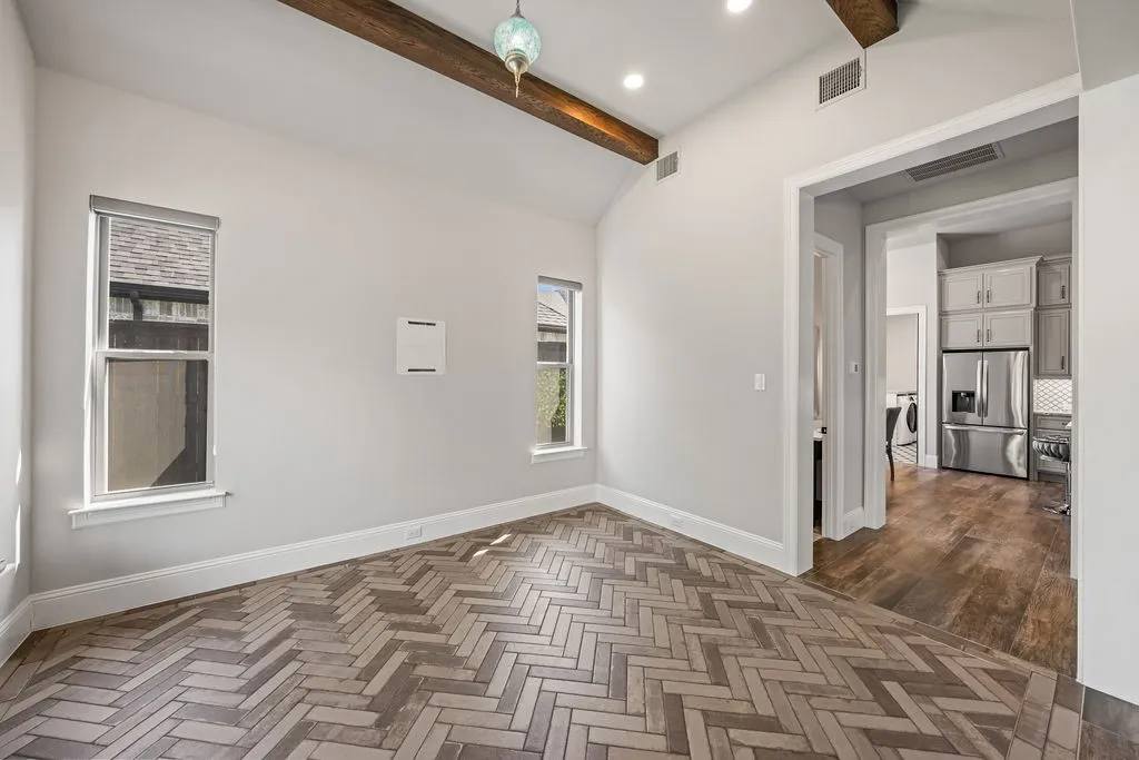 Vaulted ceiling with exposed wood beams, recessed lighting, and a decorative pendant light