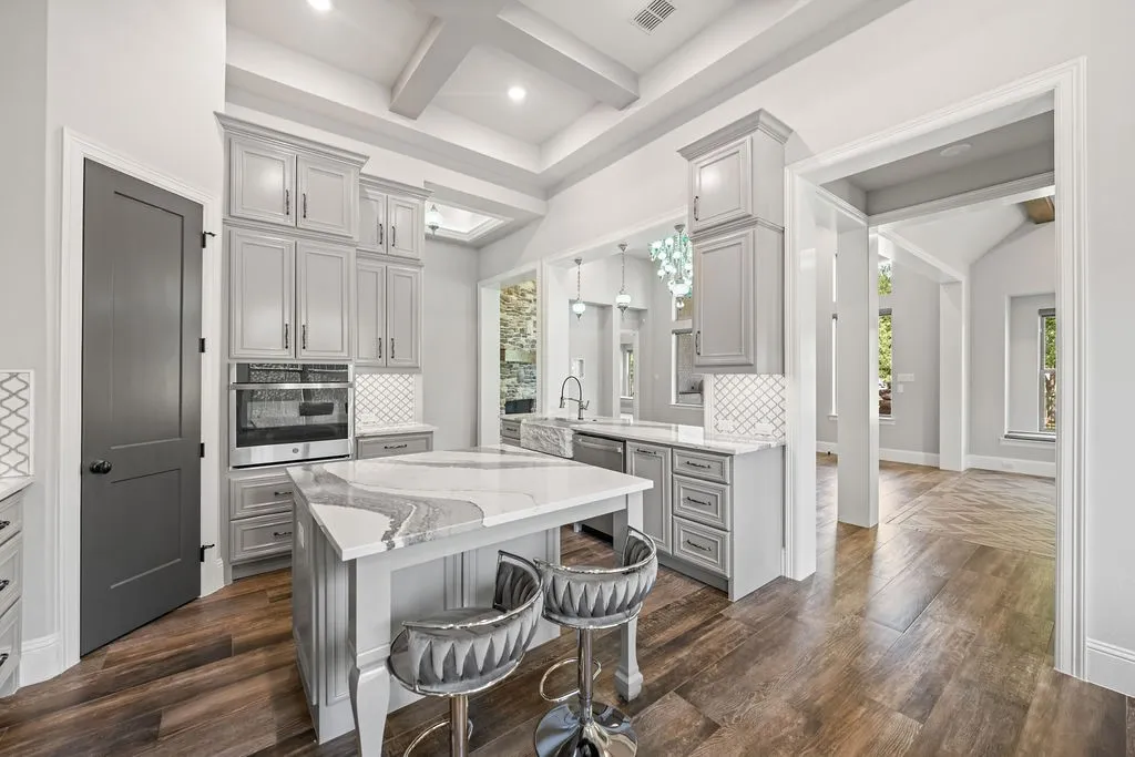Kitchen featuring a central island with countertop seating, built-in stainless steel appliances, extensive cabinetry, and wood-finish flooring