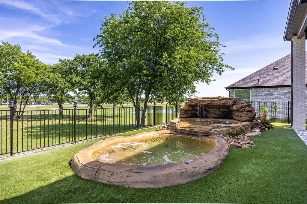 Rock-formed pond with integrated waterfall feature, surrounded by artificial turf
