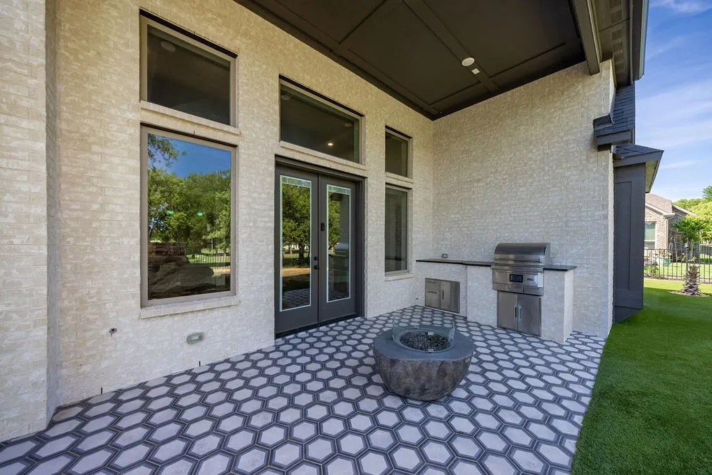 Covered patio featuring an outdoor kitchen with built-in grill, a fire pit, and patterned hexagonal tile flooring
