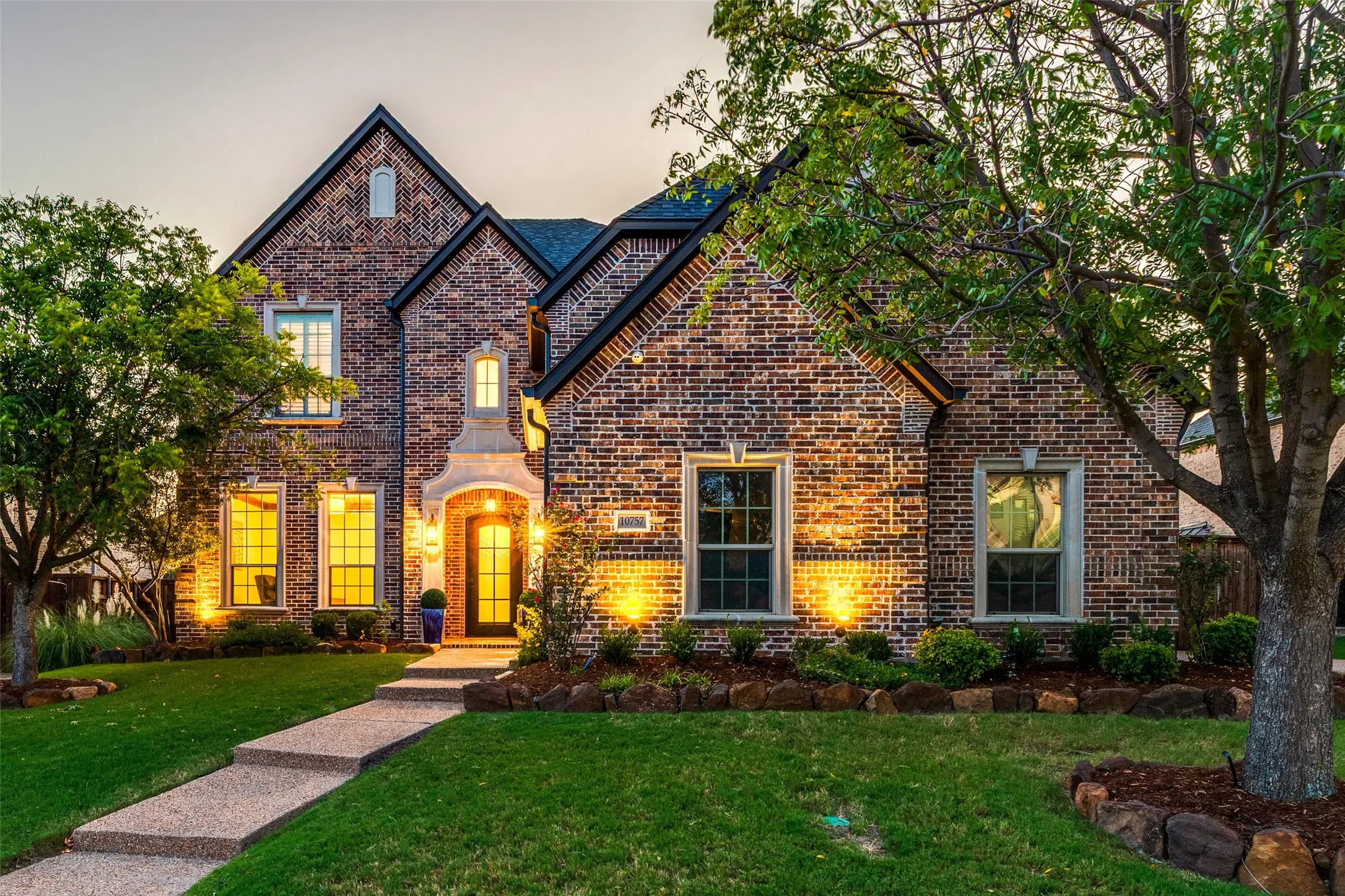 Brick exterior with gabled roof lines, featuring a stone entry archway and a dark paneled front door