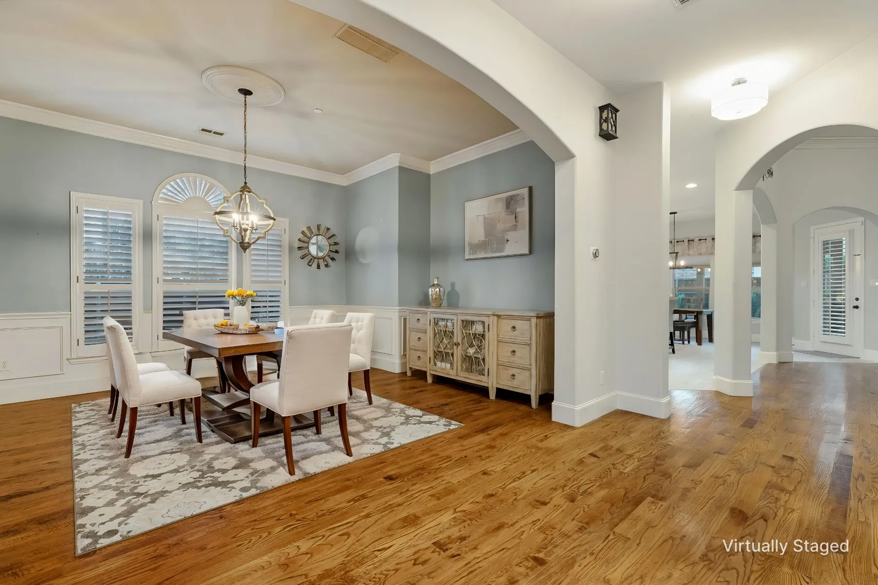 Hardwood flooring, arched doorways, intricate wall trim, decorative ceiling medallion, and plantation shutters