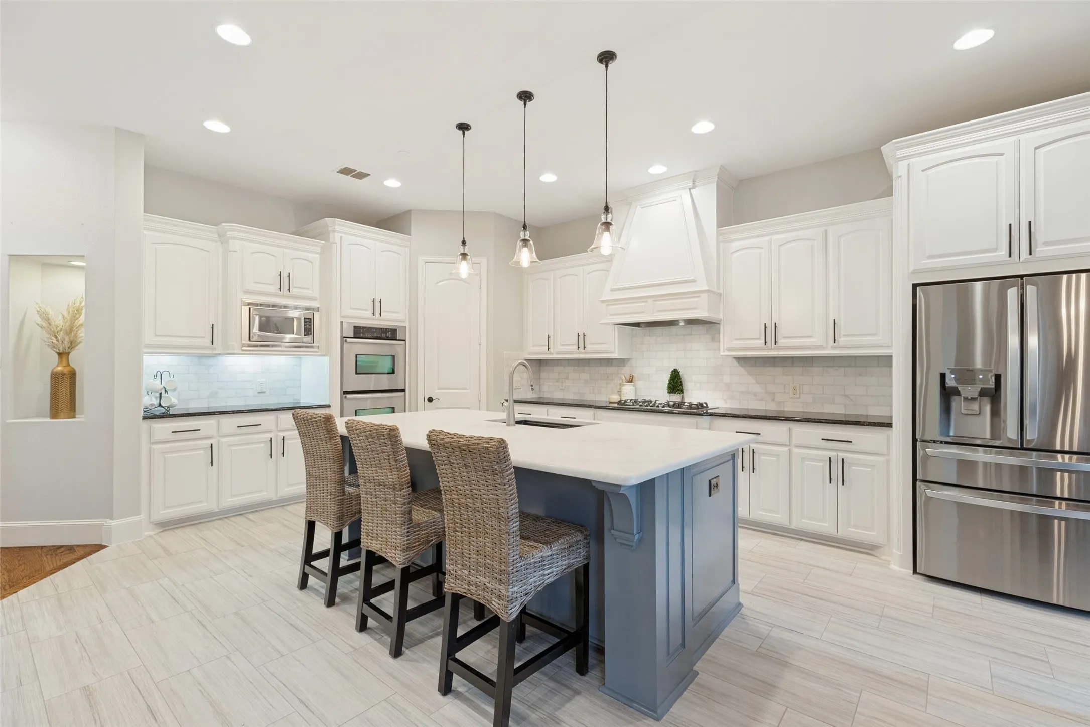 Kitchen featuring white cabinetry, a light-toned tile backsplash, stainless steel appliances, a center island with a light countertop, and recessed lighting
