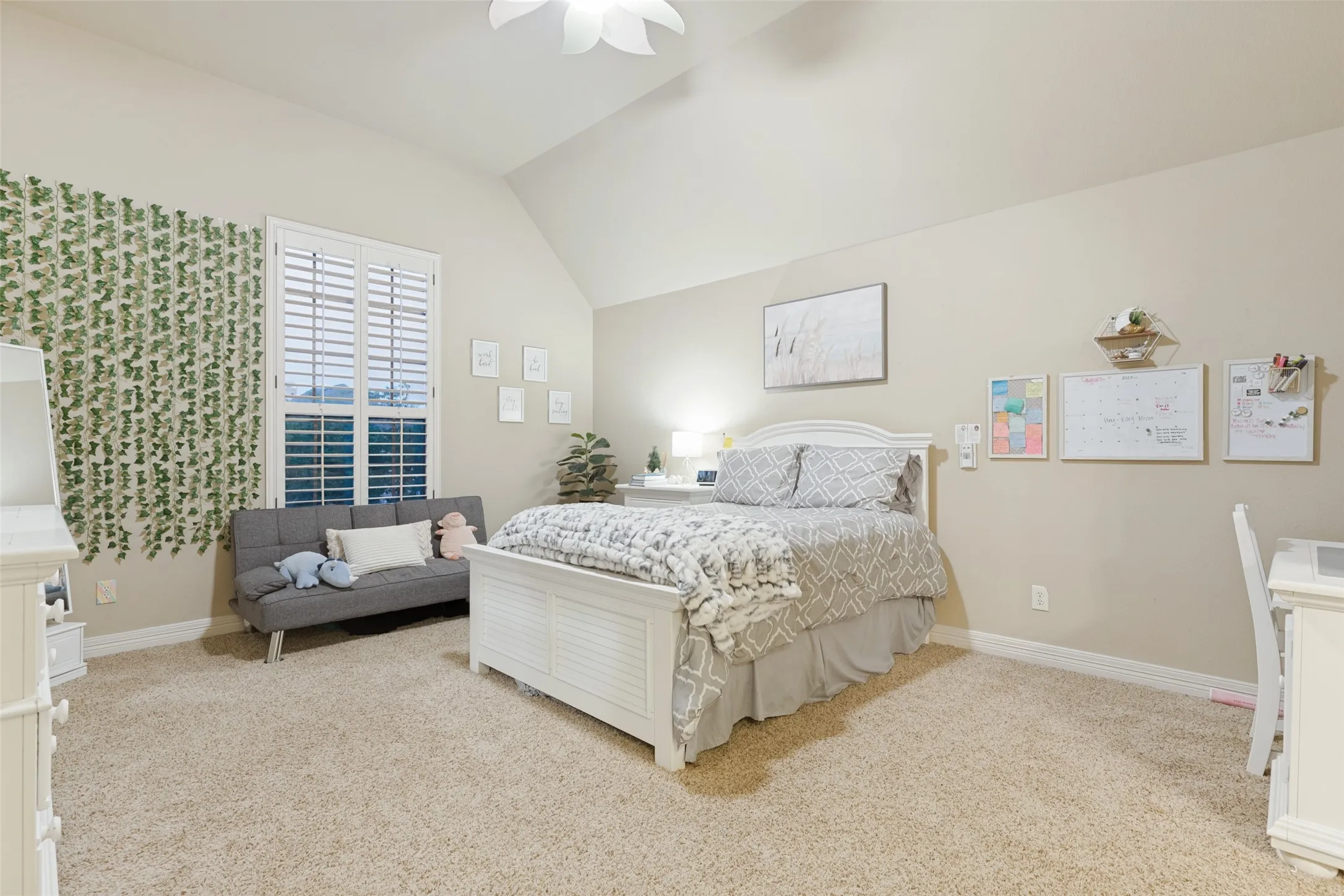 Vaulted ceiling with a ceiling fan, arched window with plantation shutters, built-in cabinetry, and neutral-toned carpeting
