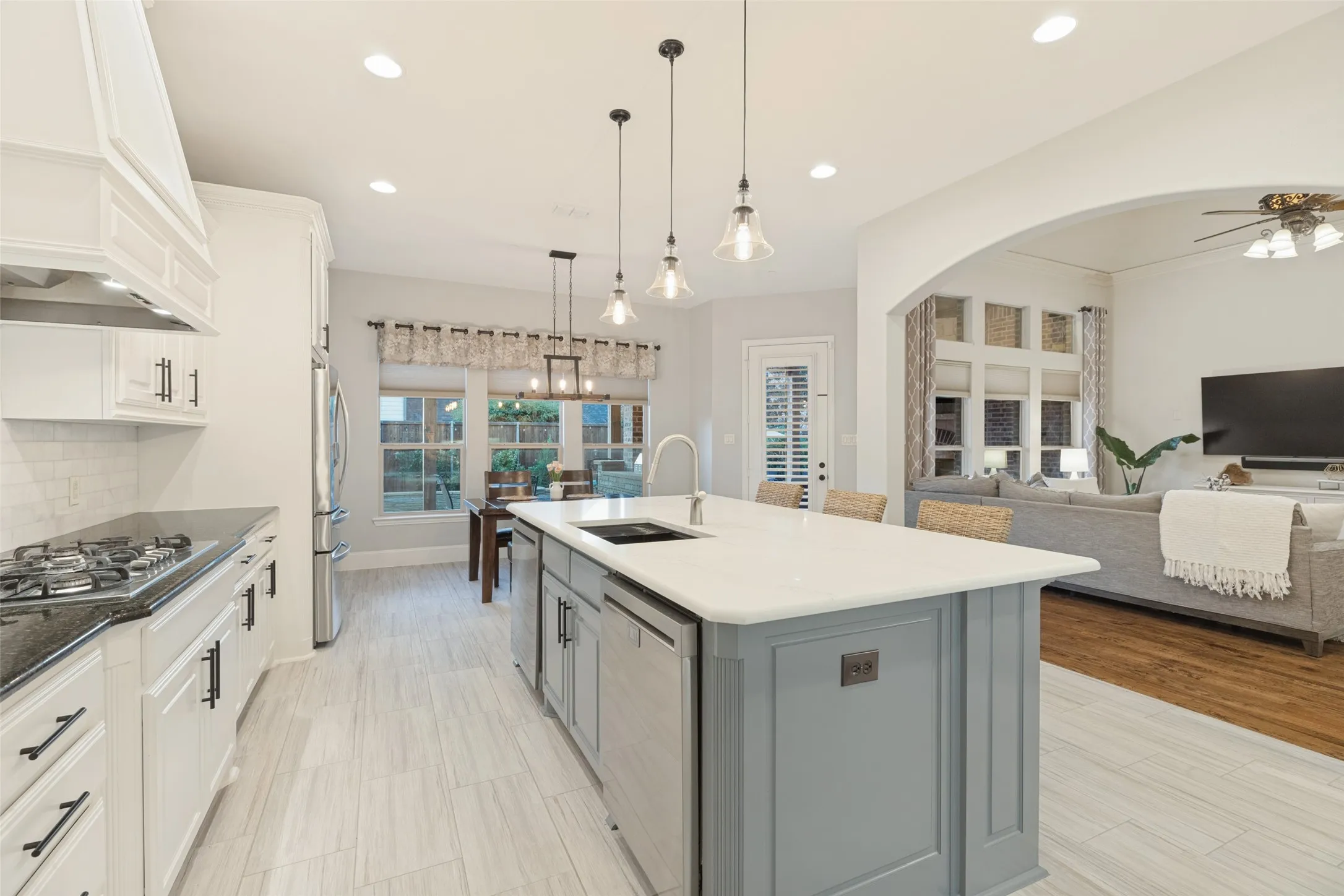 Gourmet kitchen with a large center island, built-in double ovens, a gas cooktop, white cabinetry, and a subway tile backsplash