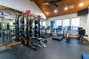 Vaulted wood-paneled ceiling, recessed lighting, ceiling fan, expansive windows, and rubberized flooring