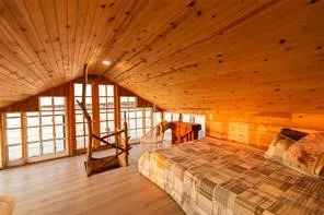 Vaulted wood-paneled ceiling, multiple windows, wood-finish flooring, and natural wood accents
