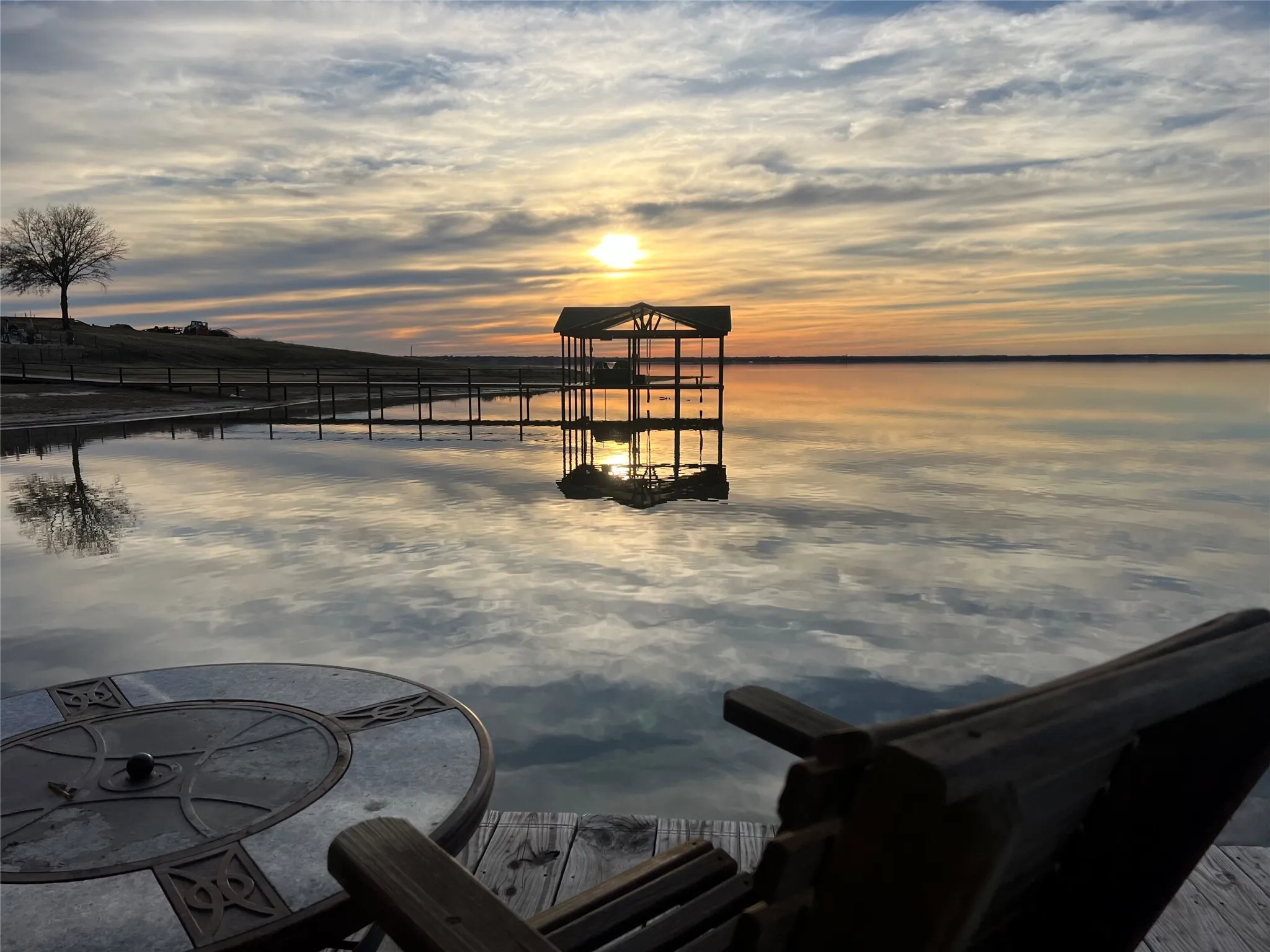 Waterfront property featuring a private dock with a covered boat slip, tranquil water reflections, and an expansive sky