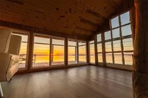 Wood-clad vaulted ceiling, wood-finish flooring, a wall of large windows, and a prominent tree-trunk architectural feature