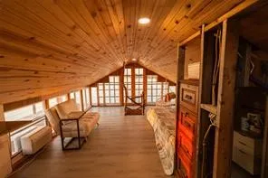 Vaulted wood-paneled ceiling, wood-finish flooring, built-in shelving, and multiple window installations