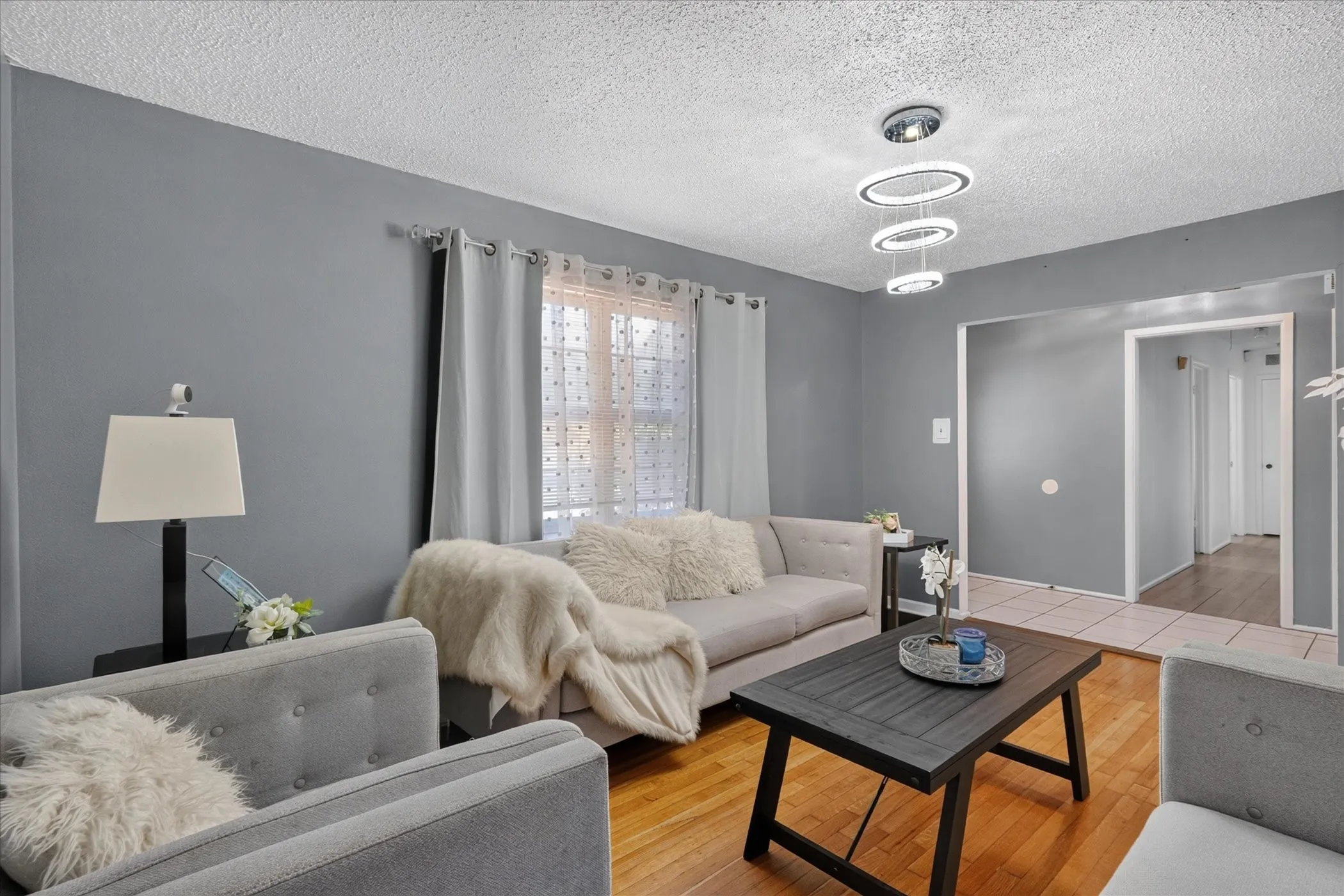 Light wood-finish flooring, neutral wall paint, and a contemporary multi-ring chandelier