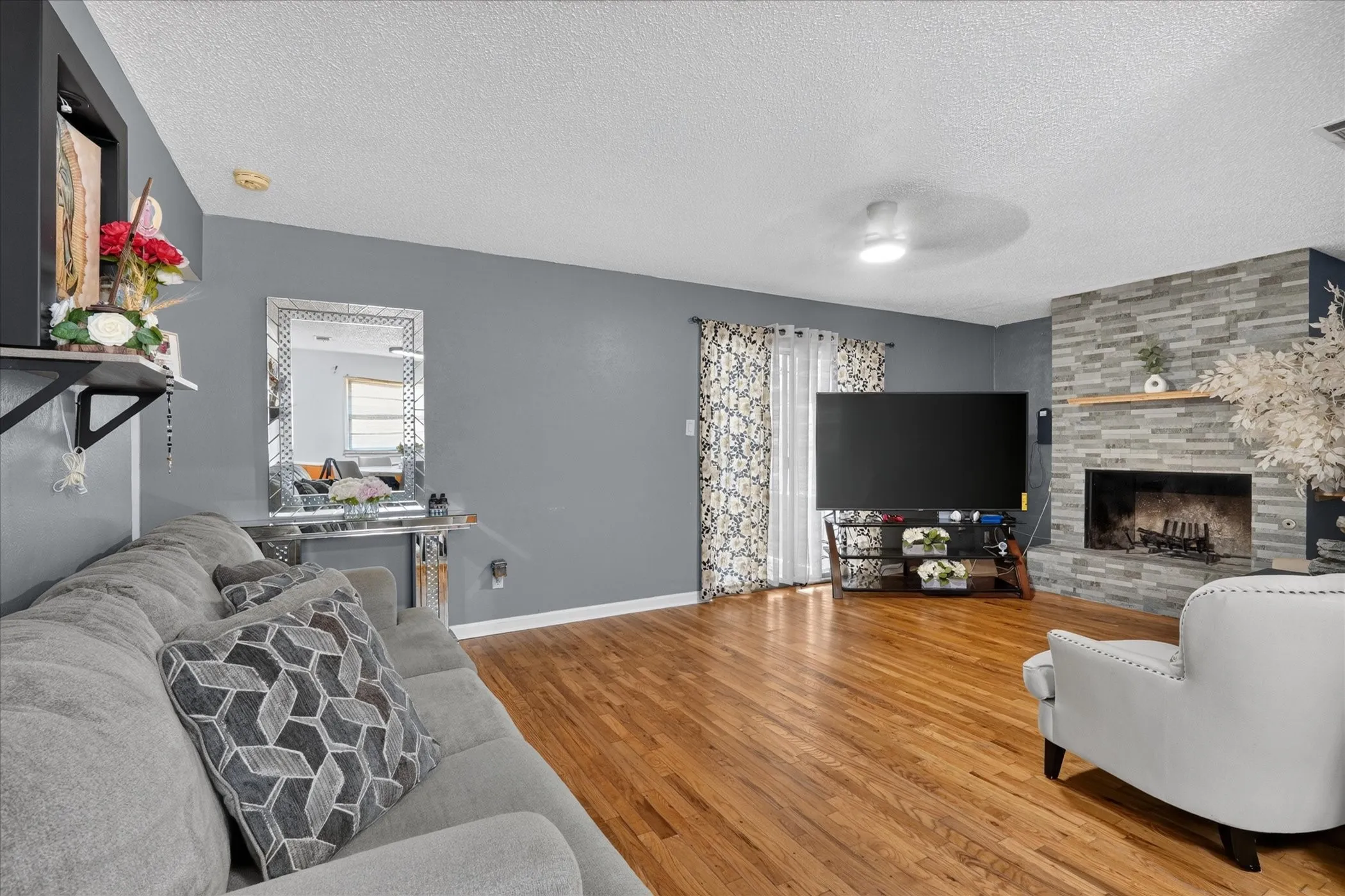 Hardwood flooring, stone fireplace with wood mantel, ceiling fan, and recessed lighting