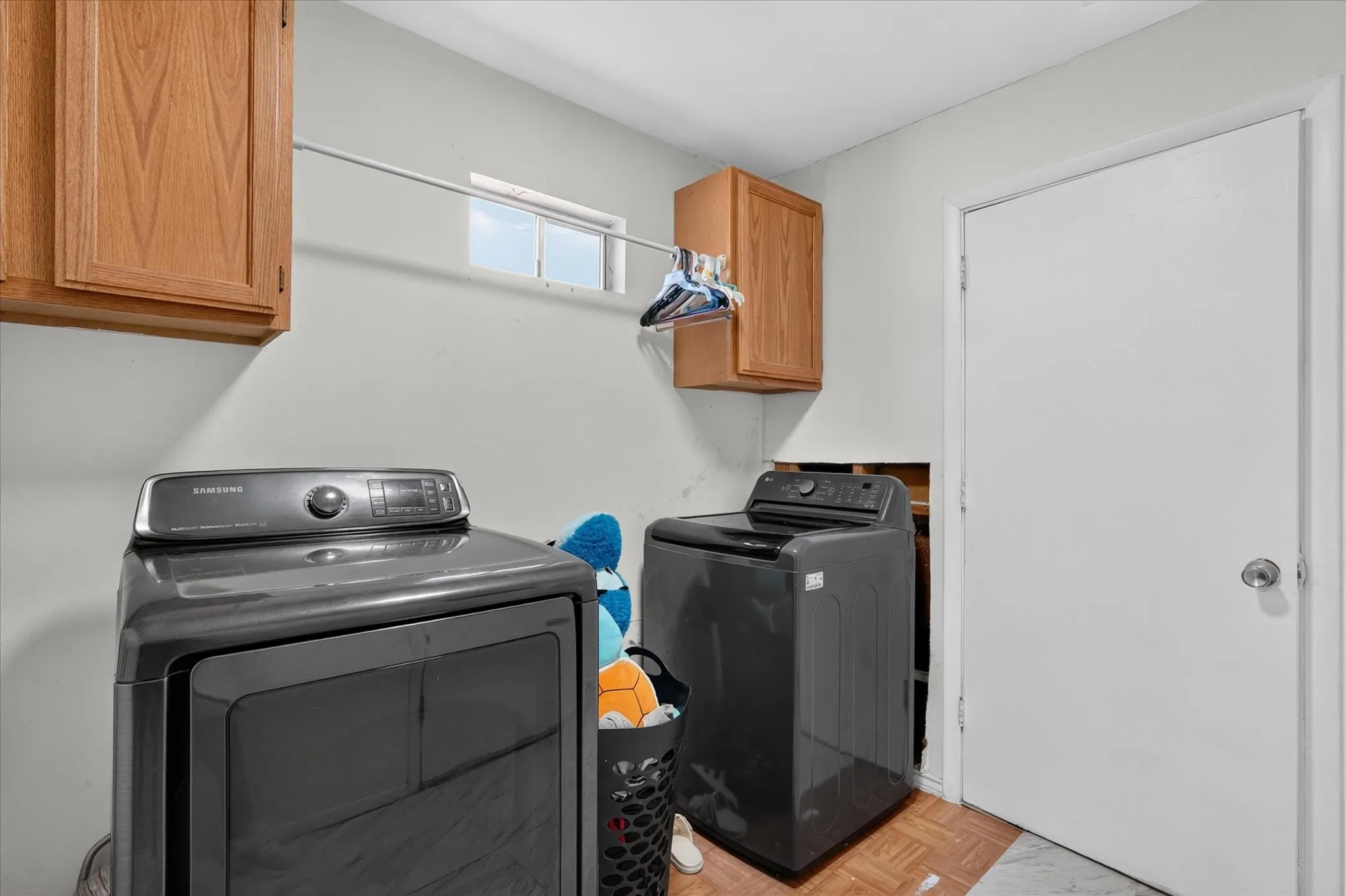 Laundry area featuring built-in wood cabinetry, a utility window, and a clothes hanging rod