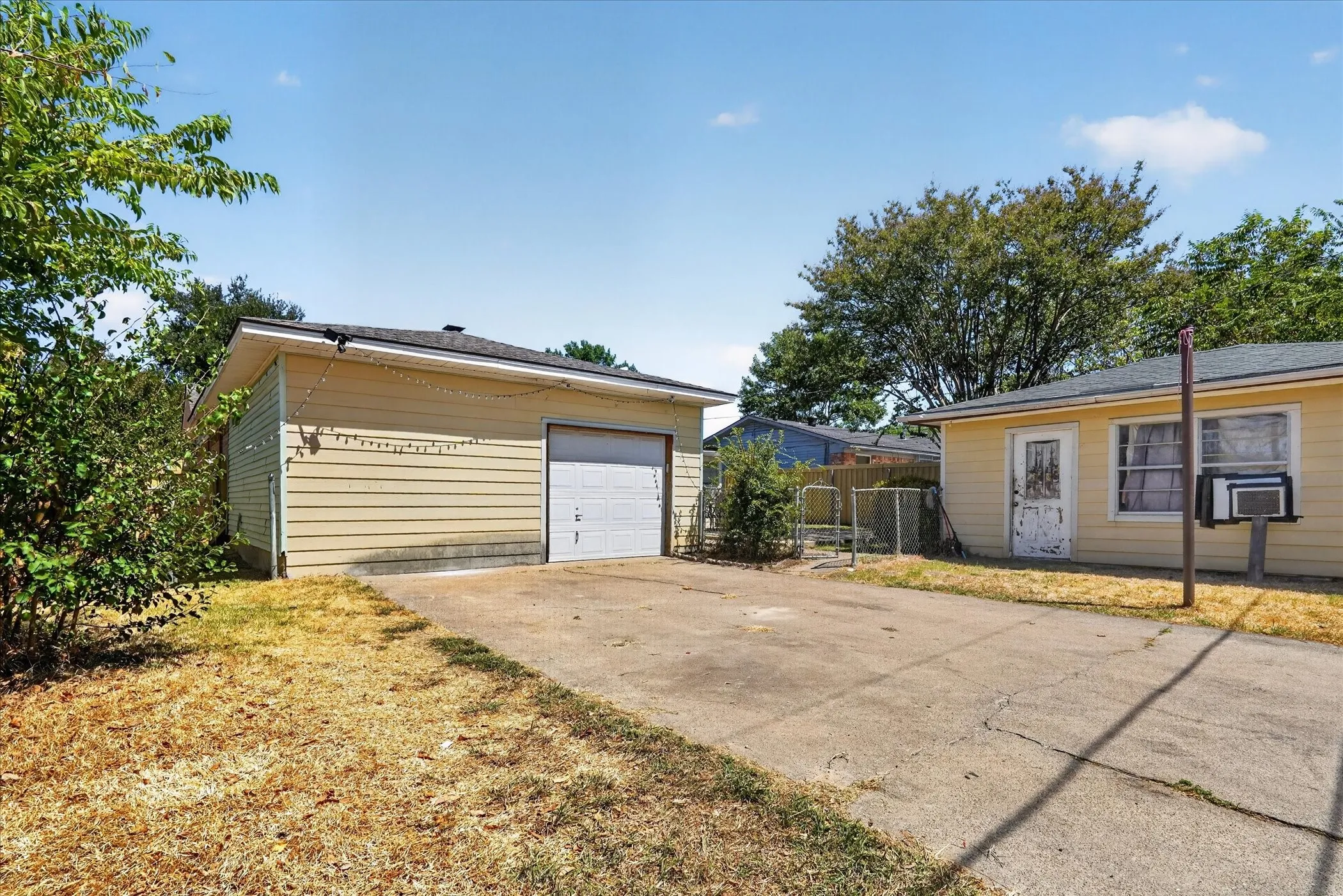 Detached garage with horizontal siding, concrete driveway, and an additional structure with horizontal siding