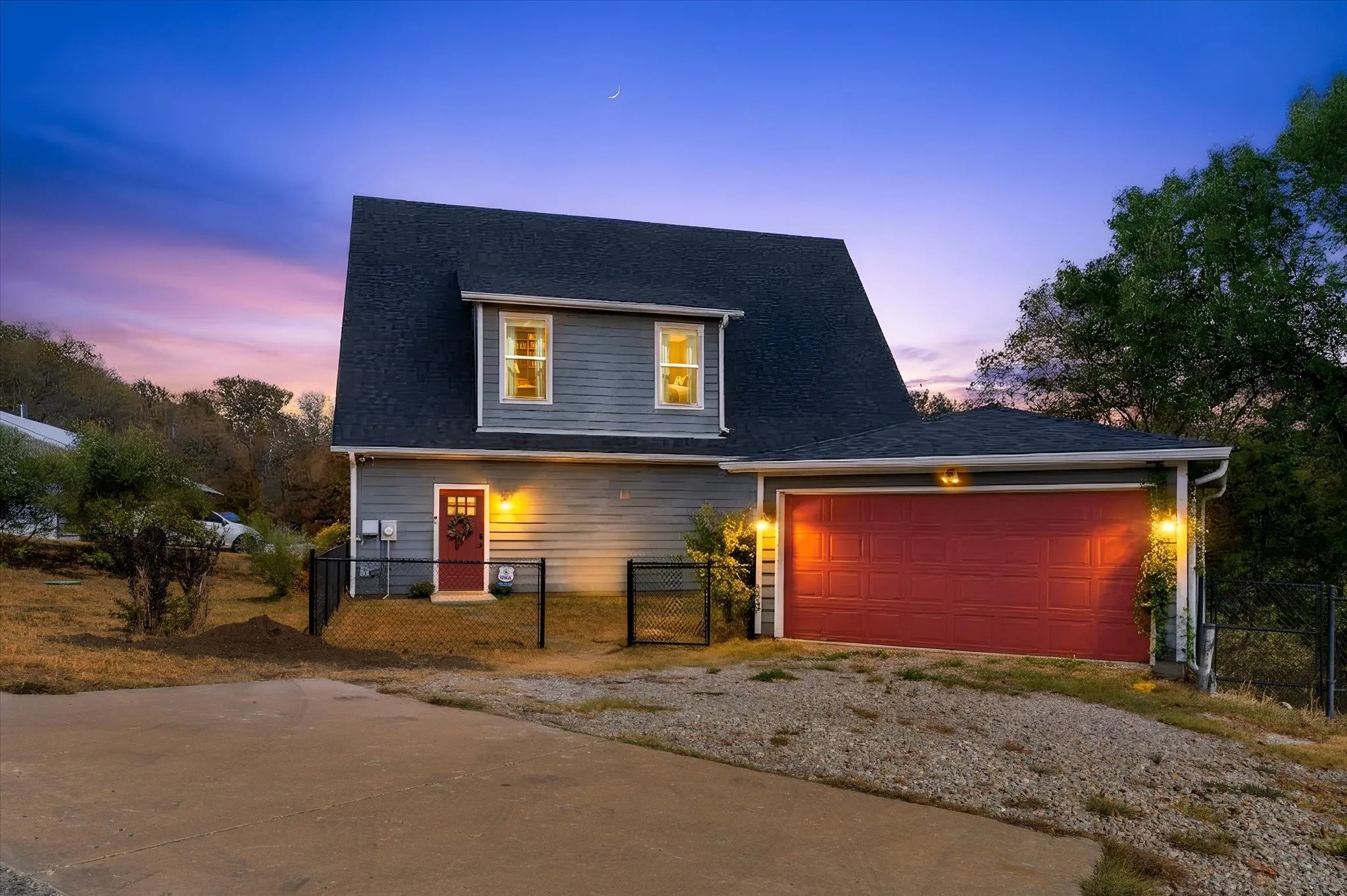 Two-story exterior with gray siding, a dark pitched roof, and a prominent red garage door