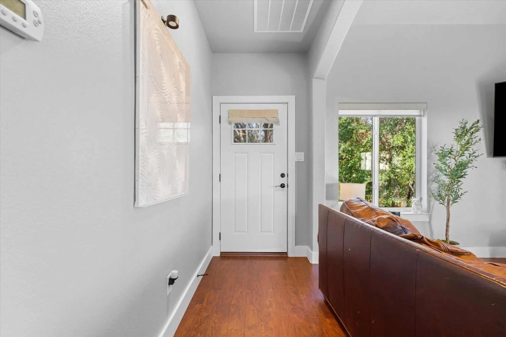 Entryway with wood-finish flooring, a white paneled door with glass inserts, and a transom window
