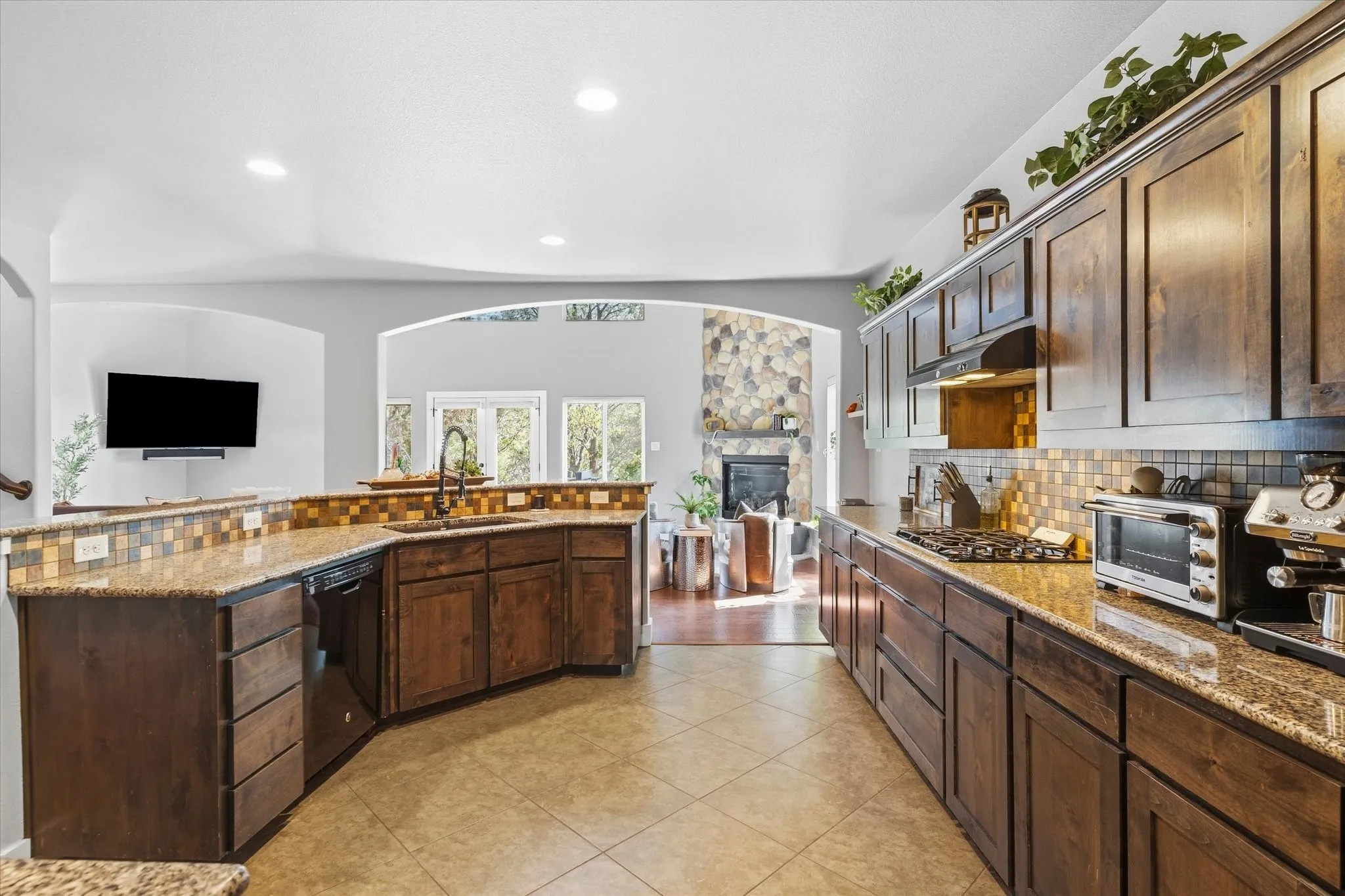 Kitchen featuring wood cabinetry, granite countertops, tile flooring, and a tile backsplash