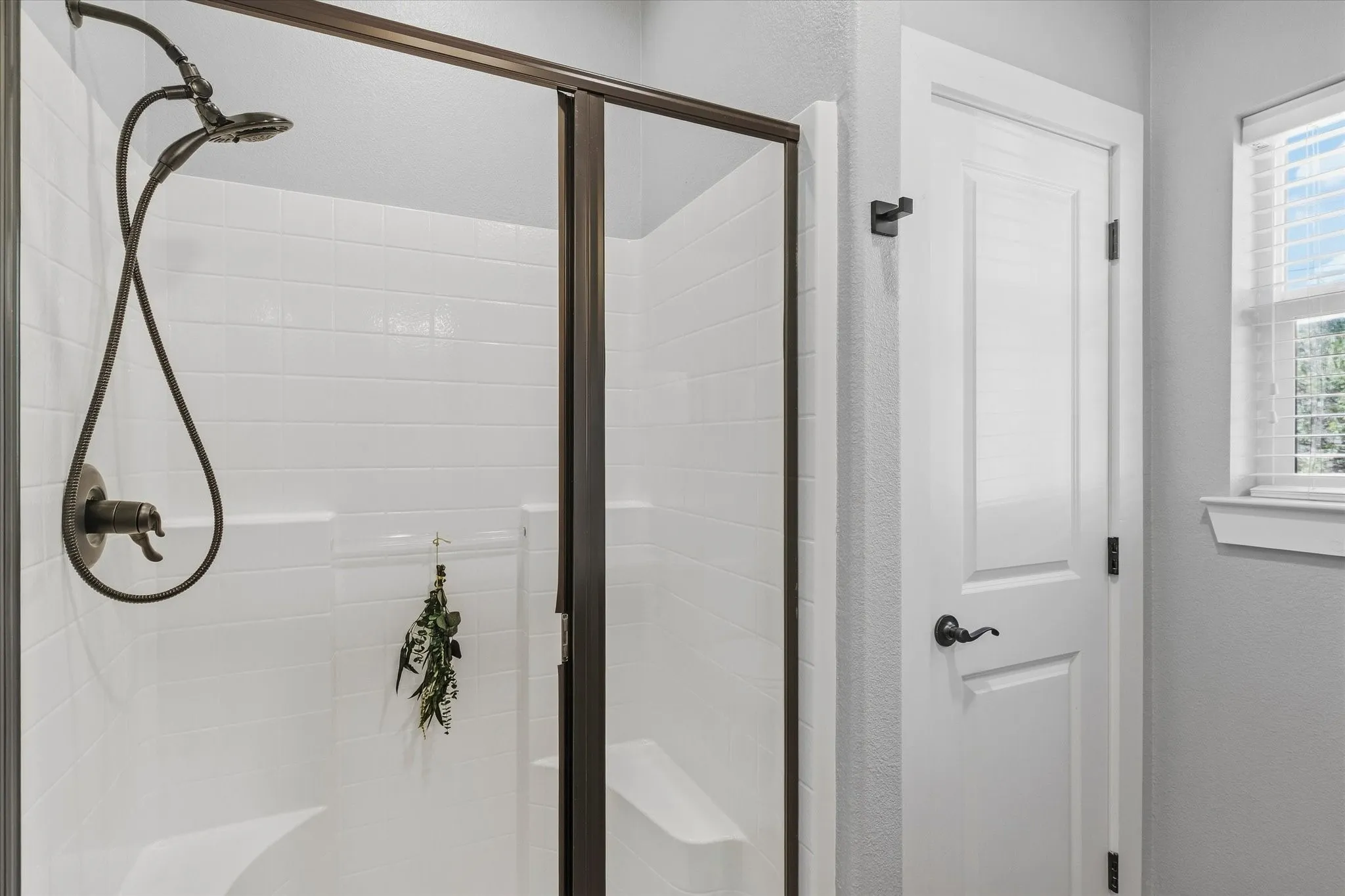 Enclosed shower with bronze-finish fixtures, a built-in bench, and white subway tile surround