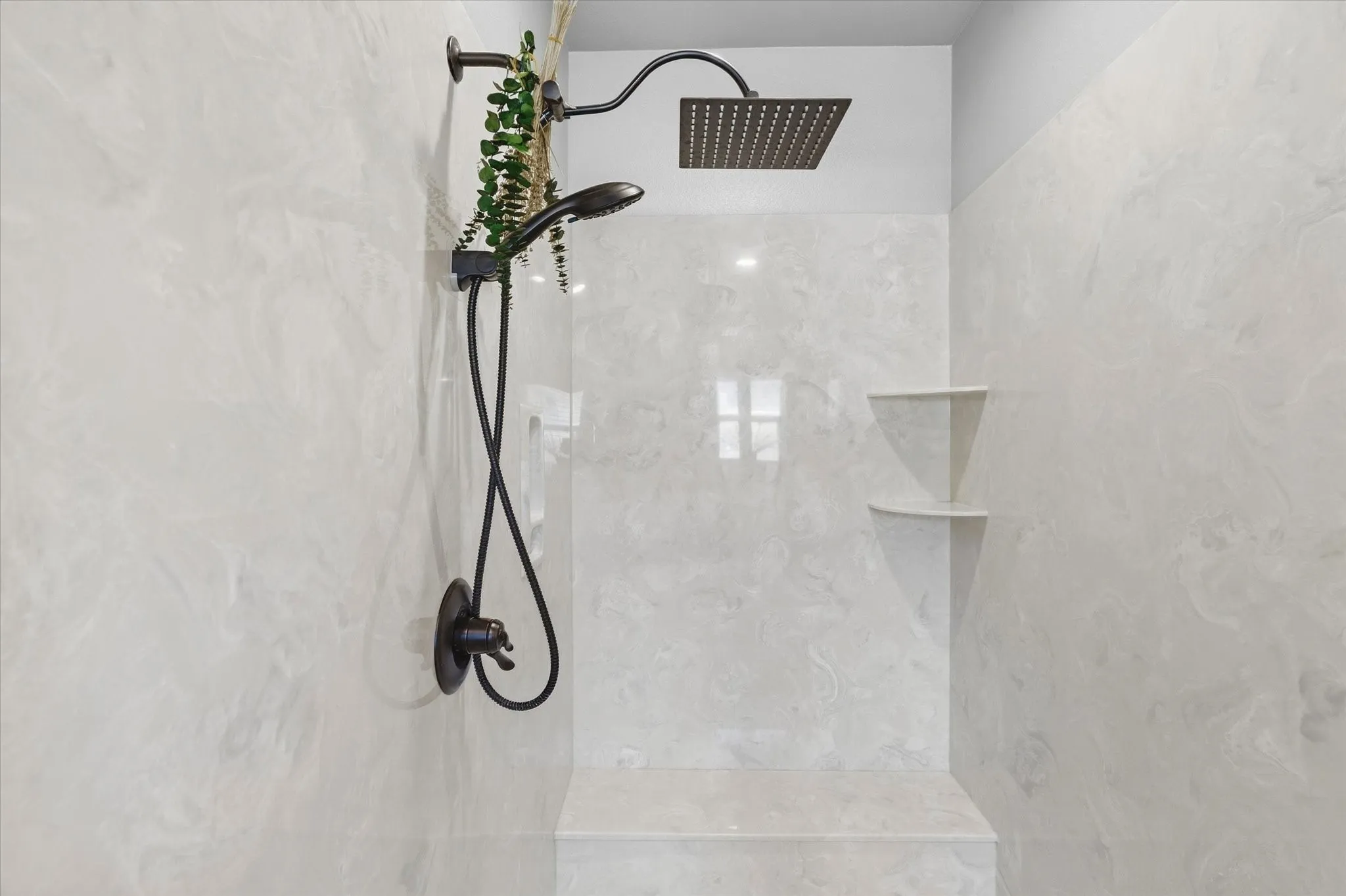 Shower with light-toned wall tile, matte black fixtures, a rainfall showerhead, and a built-in bench