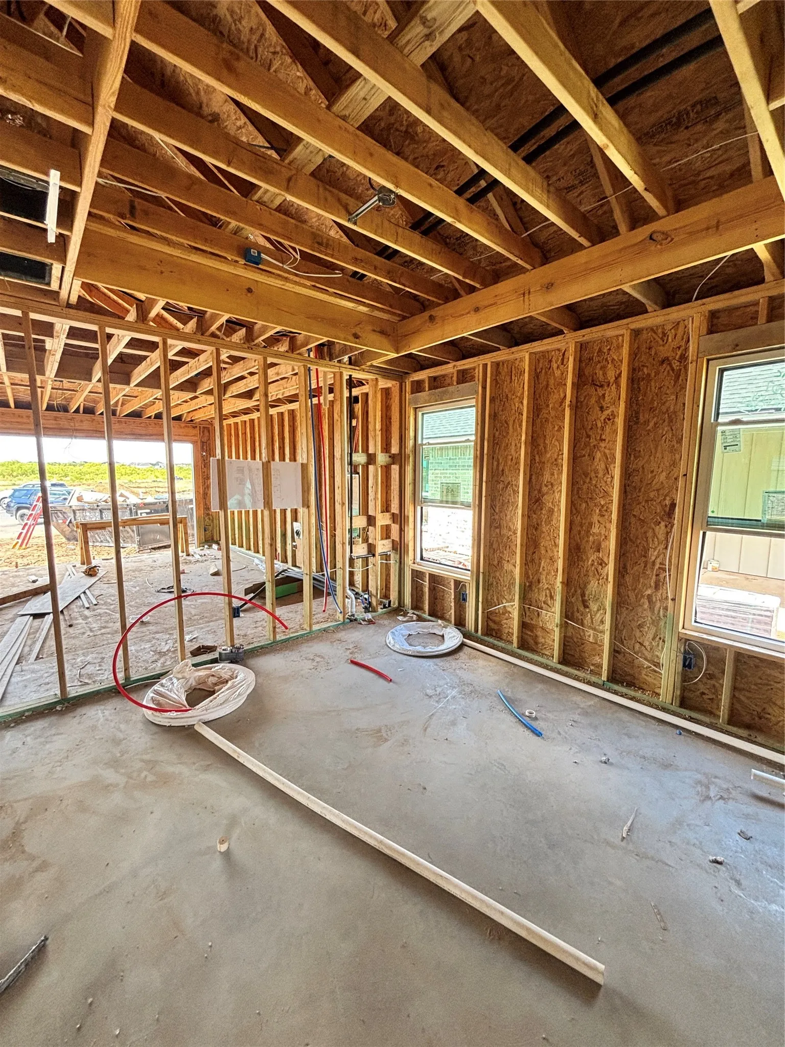 Open framing with exposed rafters, framed windows, and concrete flooring
