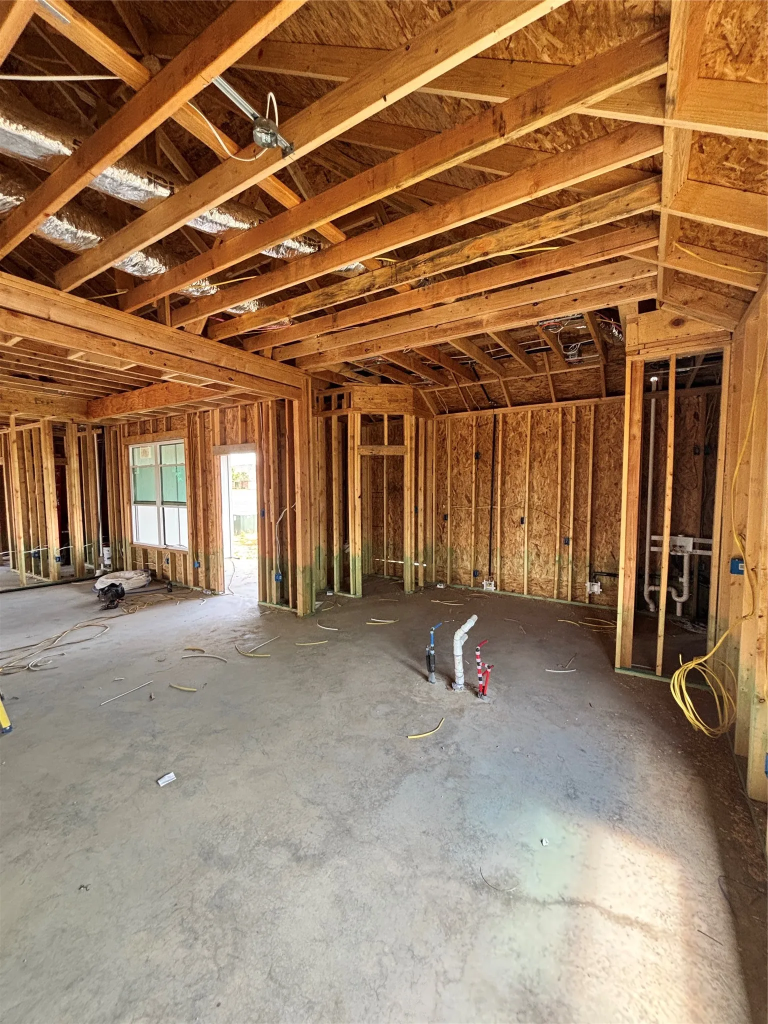 Framed interior construction with visible structural elements and a concrete slab foundation