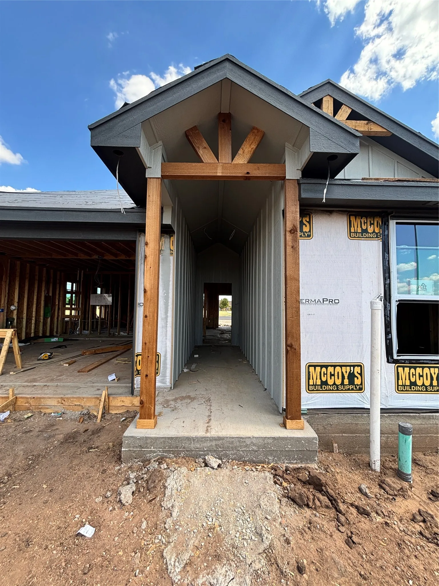 Gable roofline with exposed wood beam detailing, wood-clad support posts, concrete entryway, and horizontal siding