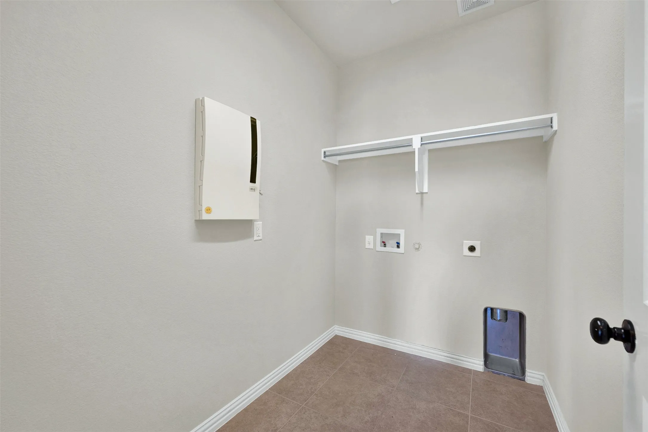 Built-in wall shelving, tile flooring, and utility hookups