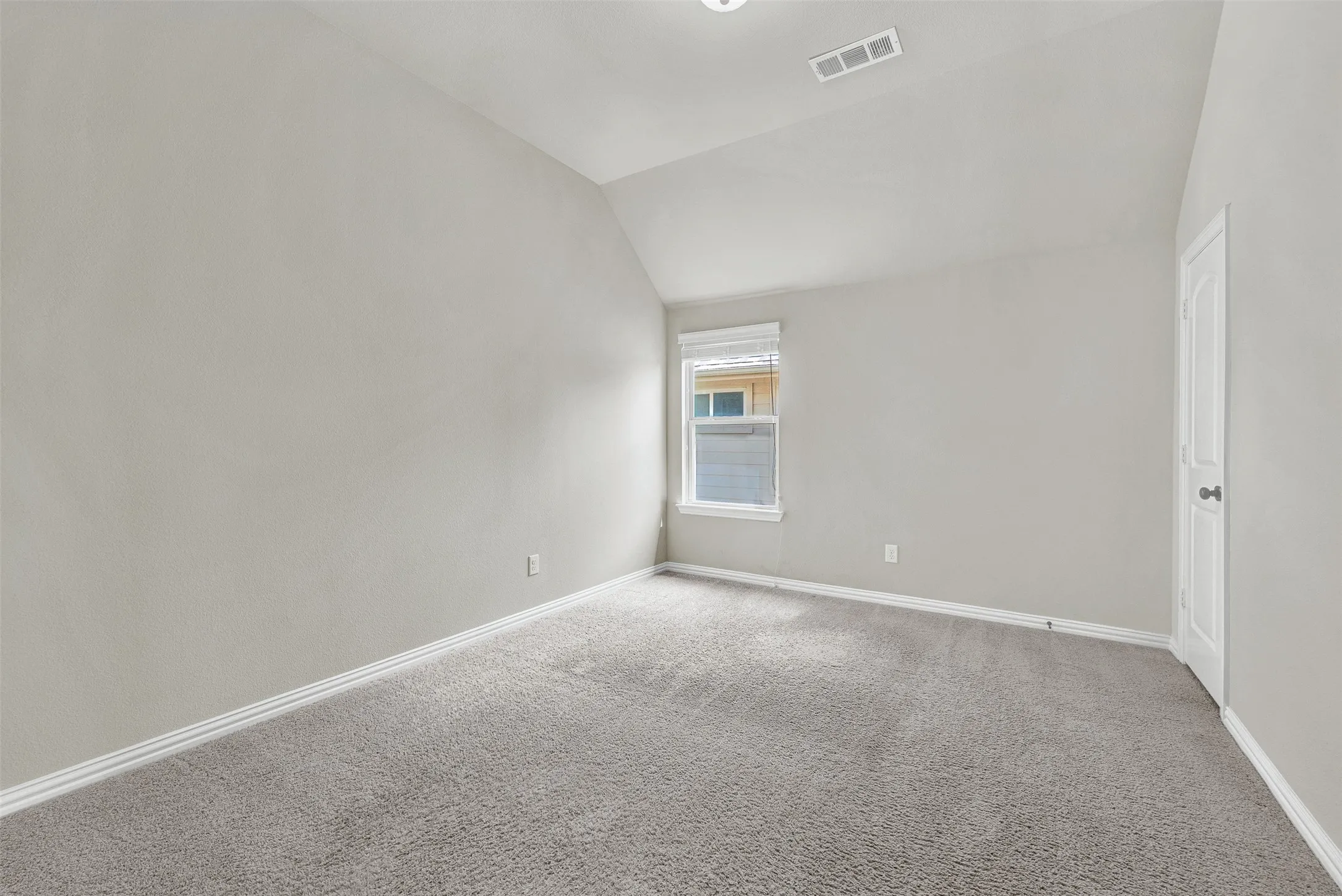 Neutral tone wall paint, vaulted ceiling, and light gray carpeting
