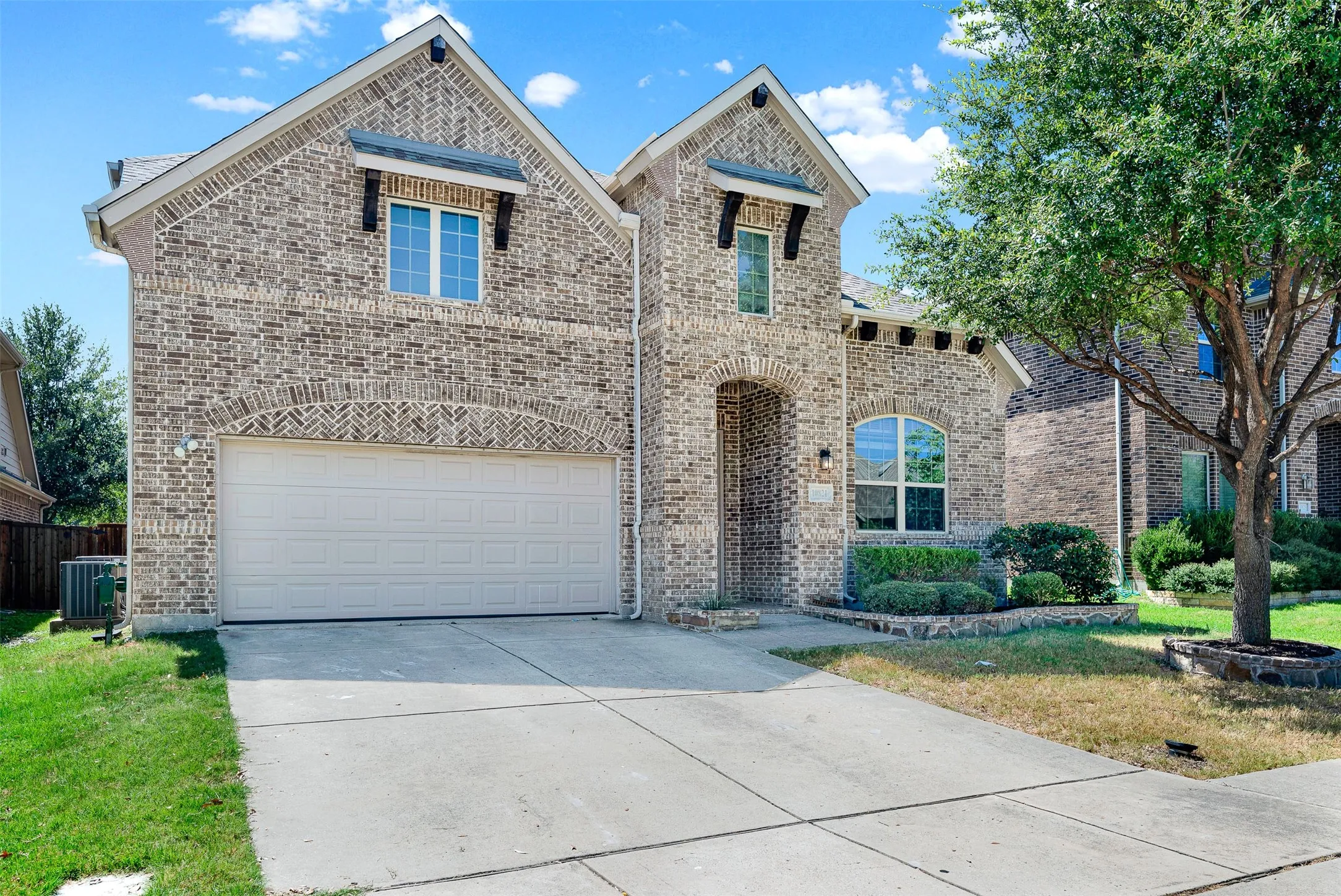 Brick exterior with arched entry, arched window, and attached garage