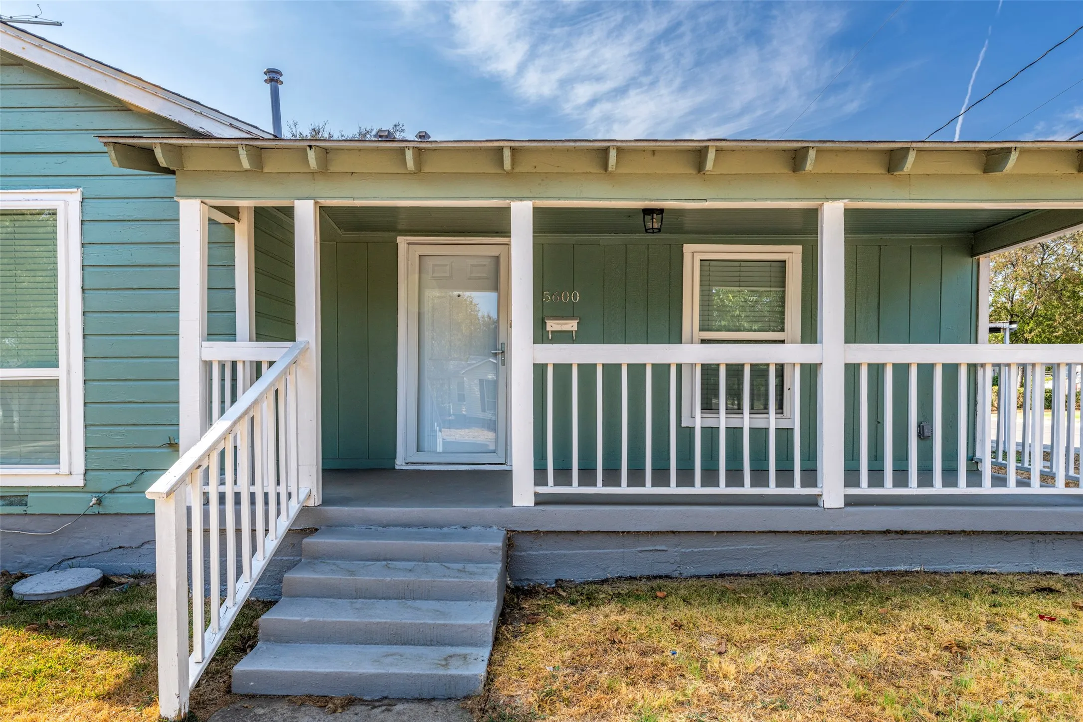 Front porch with white railings, a partial window, and a light-colored entry door