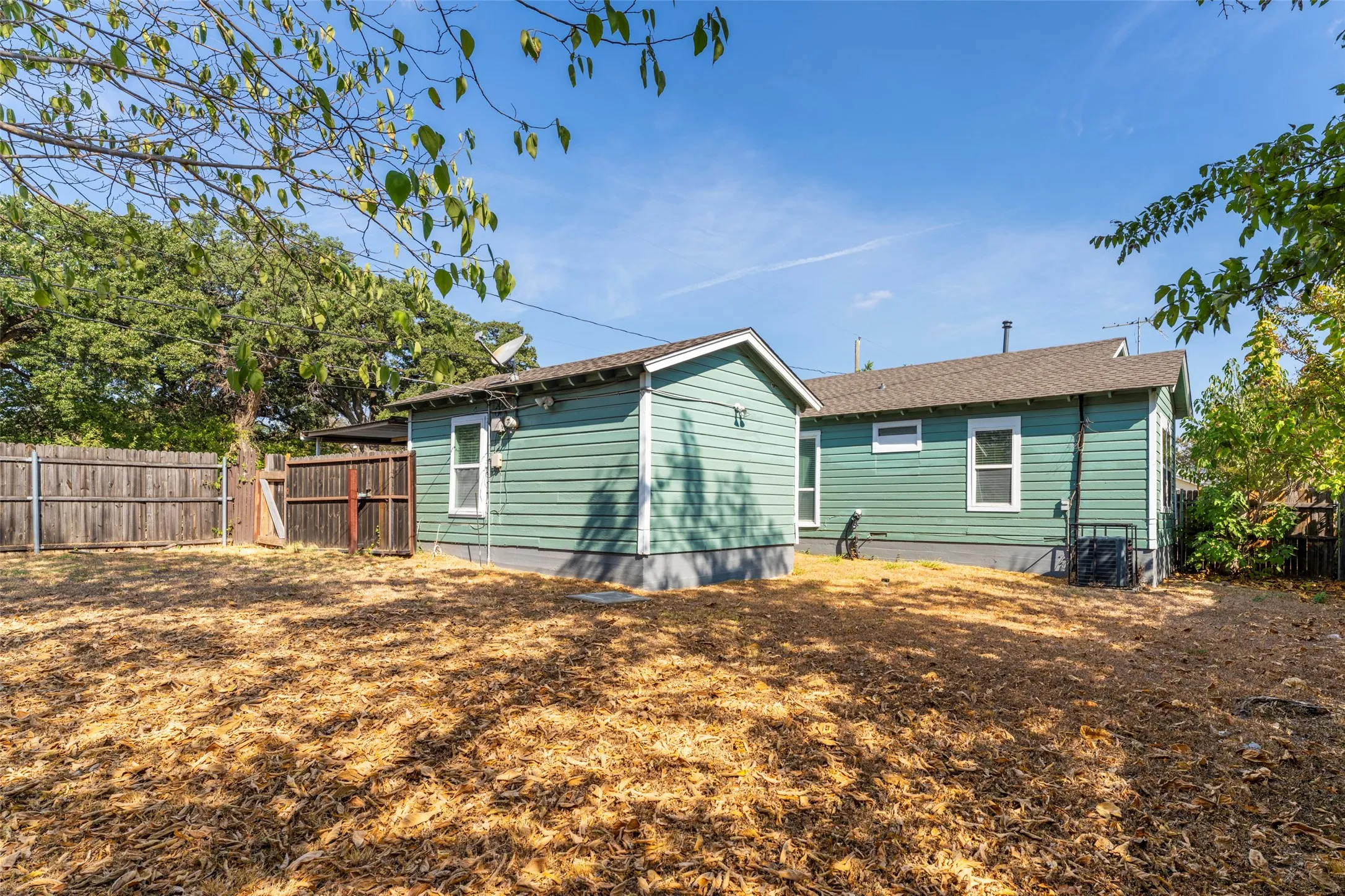Exterior featuring horizontal siding, multiple windows with white trim, and a fenced perimeter