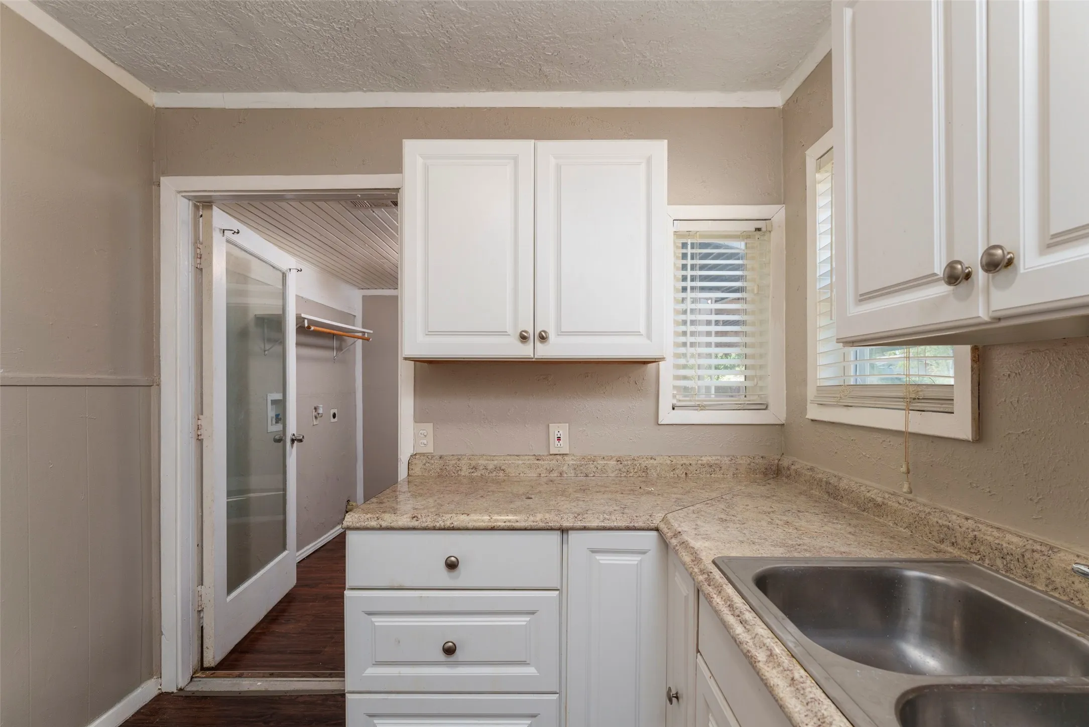 White cabinetry with brushed nickel hardware, light-toned countertop, and a double-basin stainless steel sink