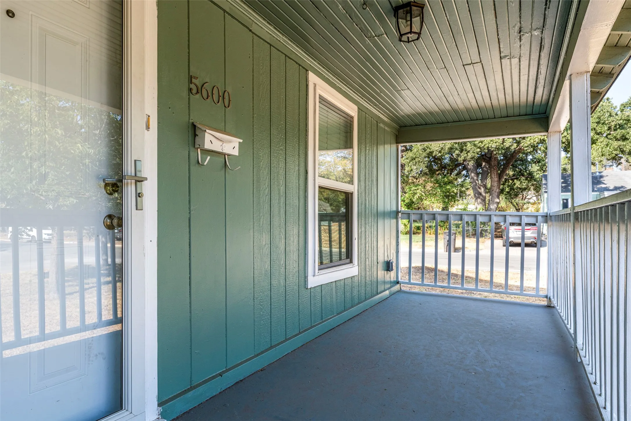 Covered front porch featuring a wooden plank ceiling and railing