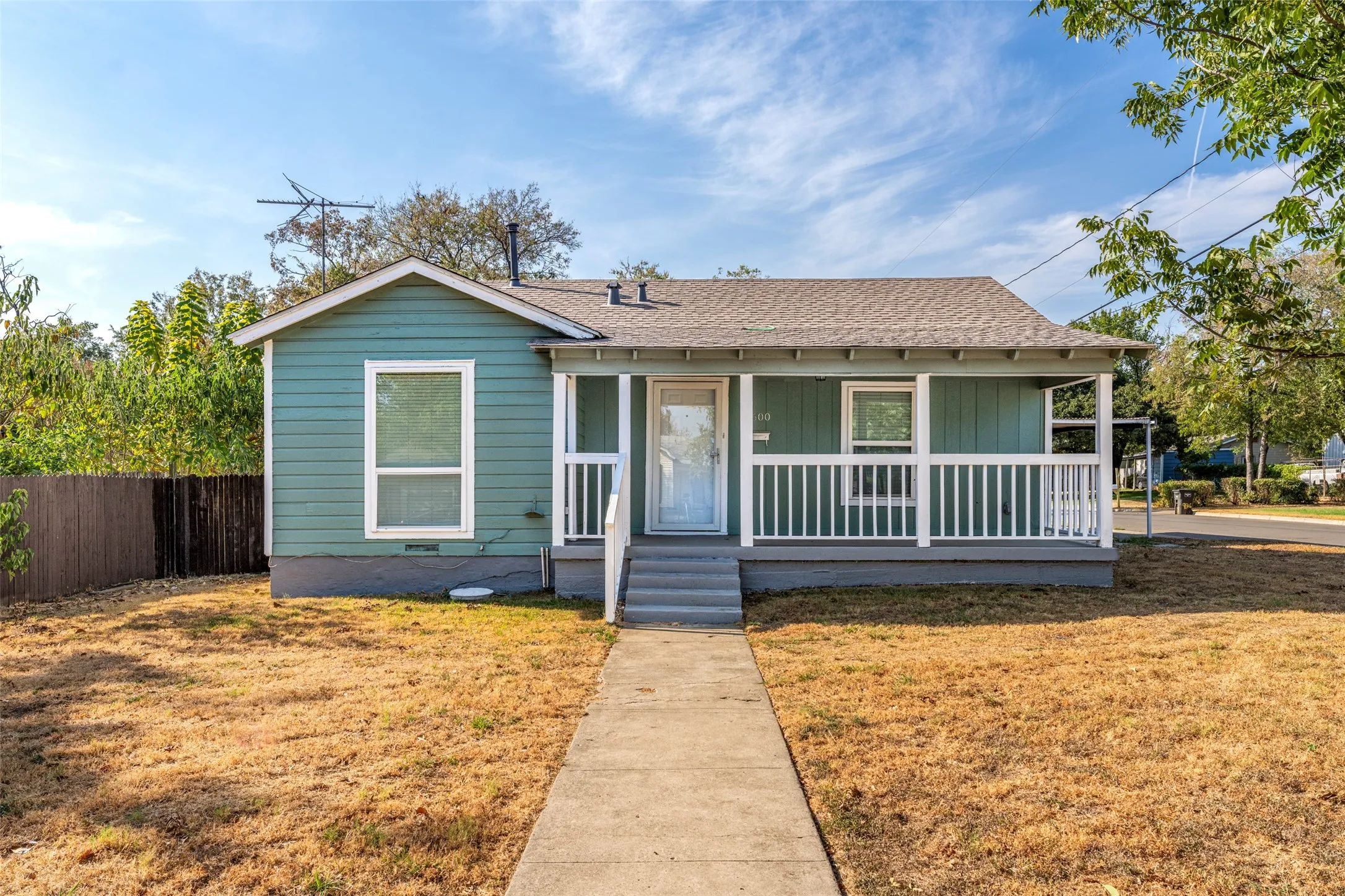 Light blue exterior siding, white trim, covered front porch, concrete pathway, and a shingled roof