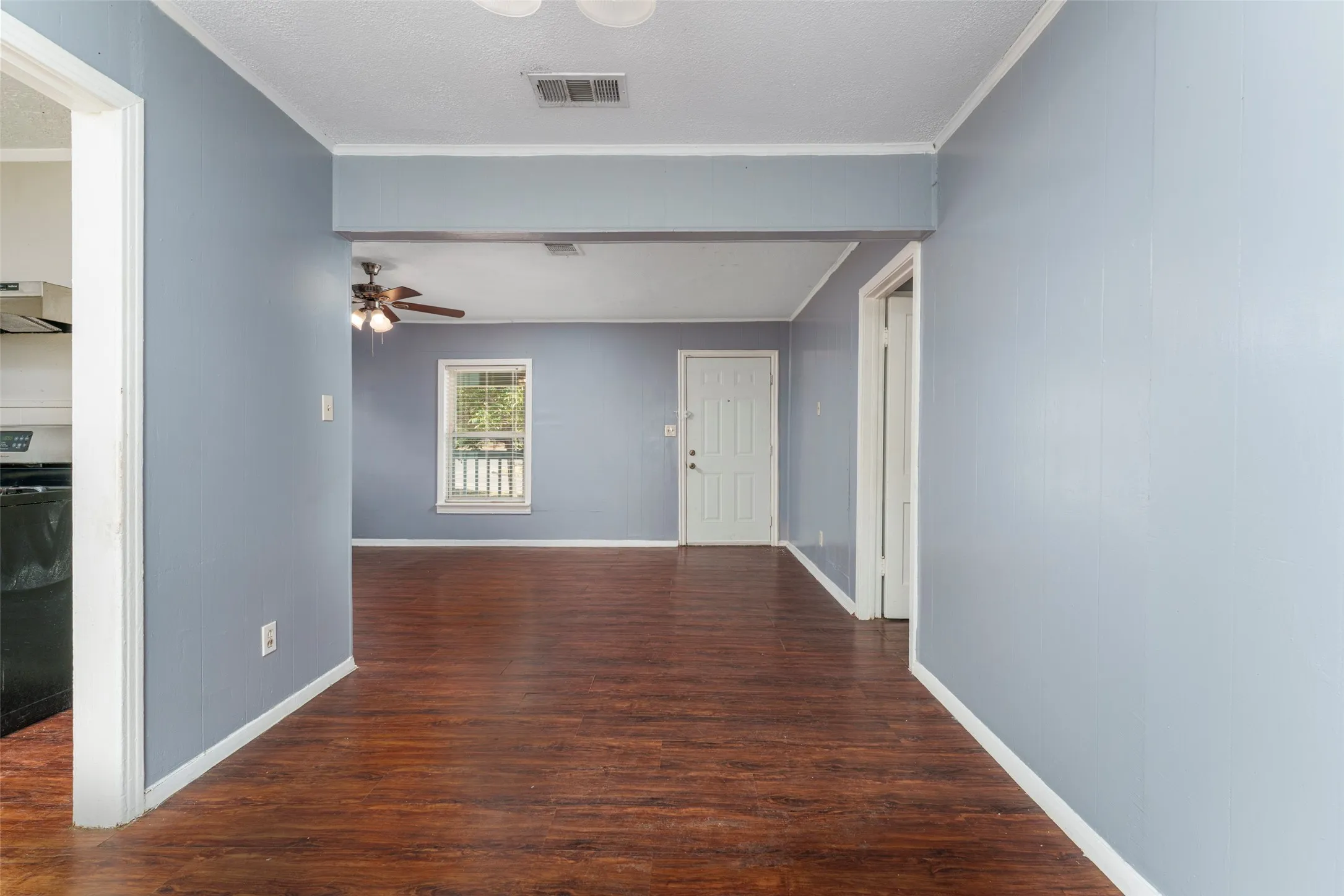 Wood-finish flooring throughout, light blue wall paint, white trim, and a white paneled door