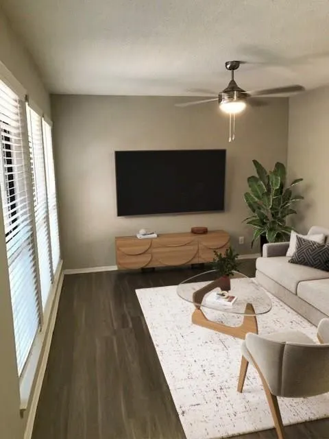 Wood-finish flooring throughout, ceiling fan with integrated lighting, and multiple windows with horizontal blinds
