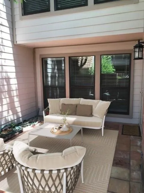 Covered patio with integrated outdoor lighting, three large windows, and a paved and tiled floor