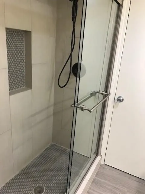 Glass-enclosed shower with a built-in niche featuring mosaic tile
