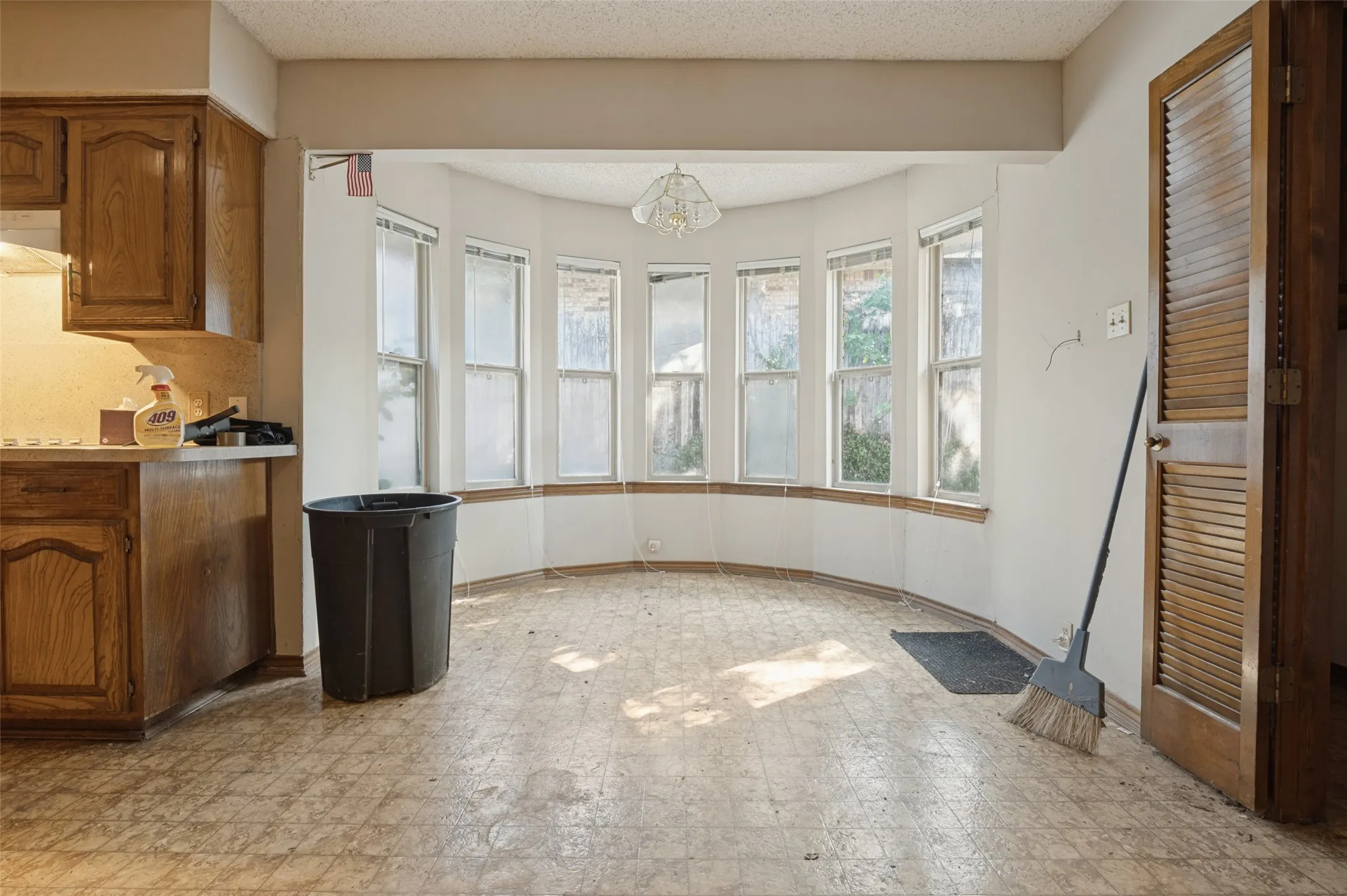Bay window feature with multiple panes, kitchen cabinetry with wood-finish doors, and louvered bifold doors