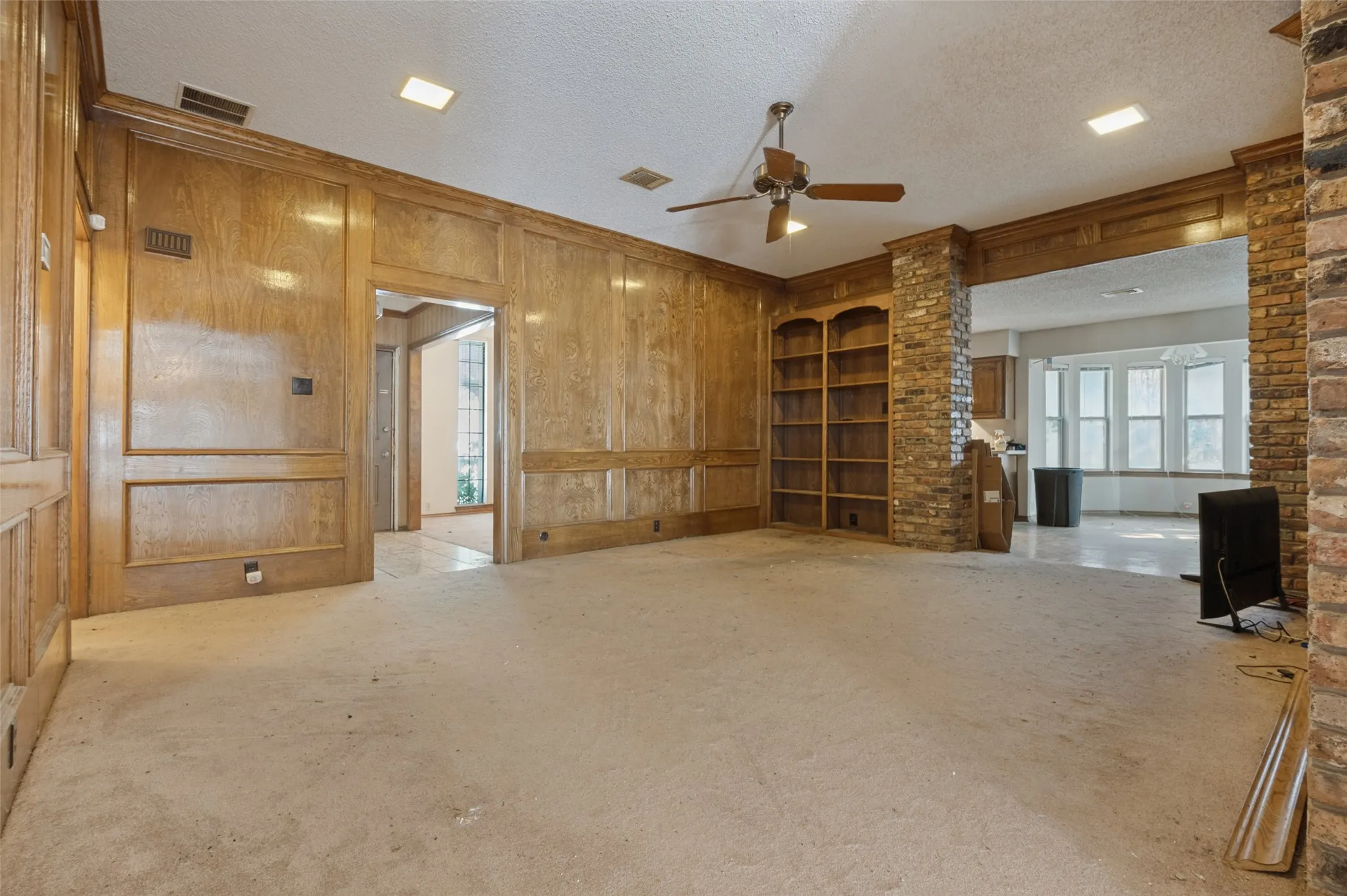 Wood paneling and built-in shelving complement the brick-clad archway and structural columns