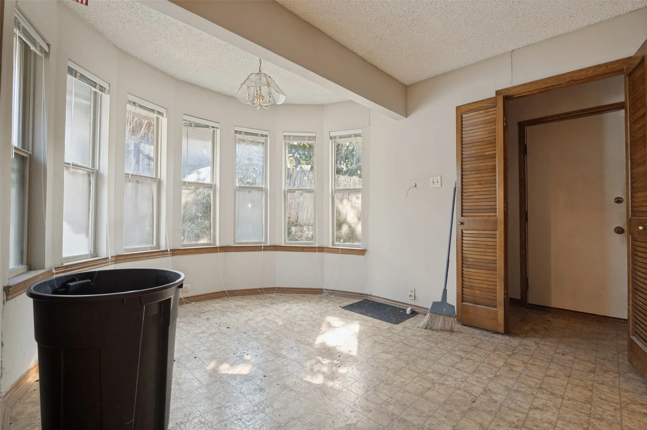 Bay window feature with multiple vertical windows, louvered bi-fold doors, and a ceiling-mounted light fixture