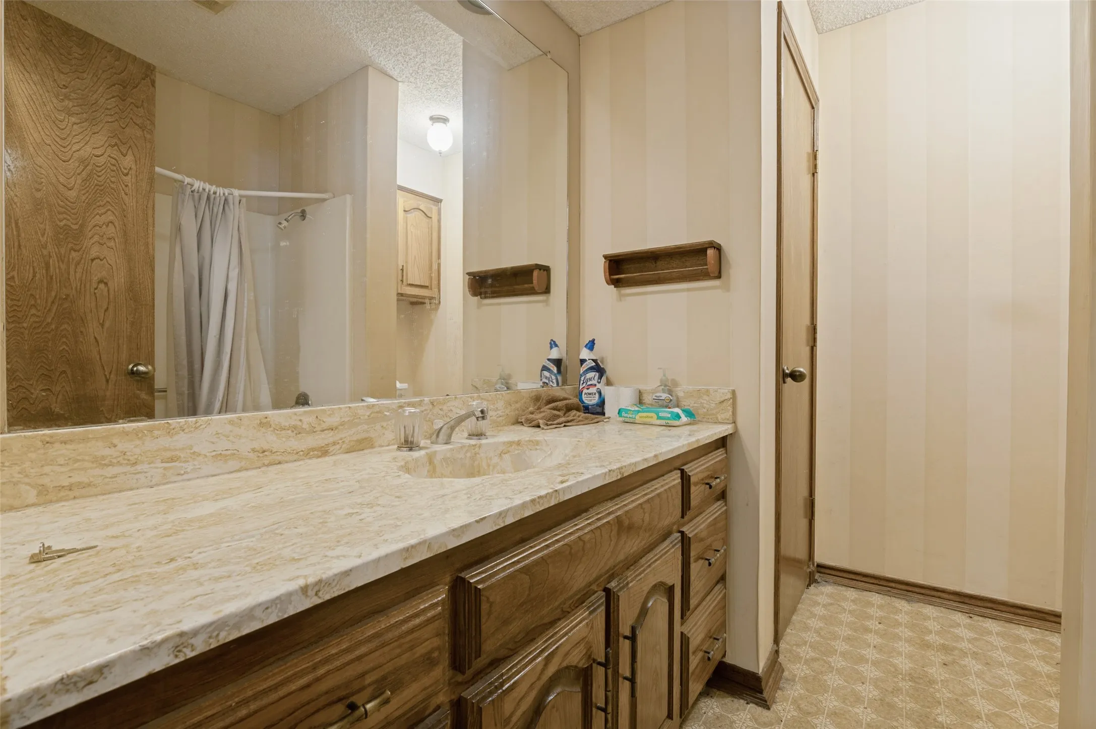Vanity with a polished stone countertop, integrated sink, and wood-finish cabinetry
