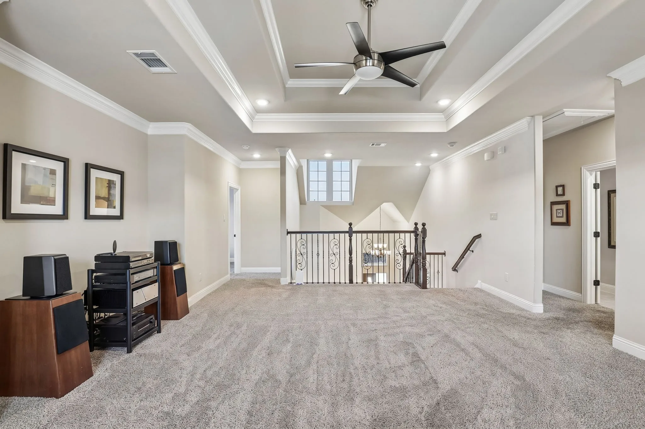Tray ceiling with recessed lighting and ceiling fan, carpeted flooring, white crown molding, and wrought iron balusters