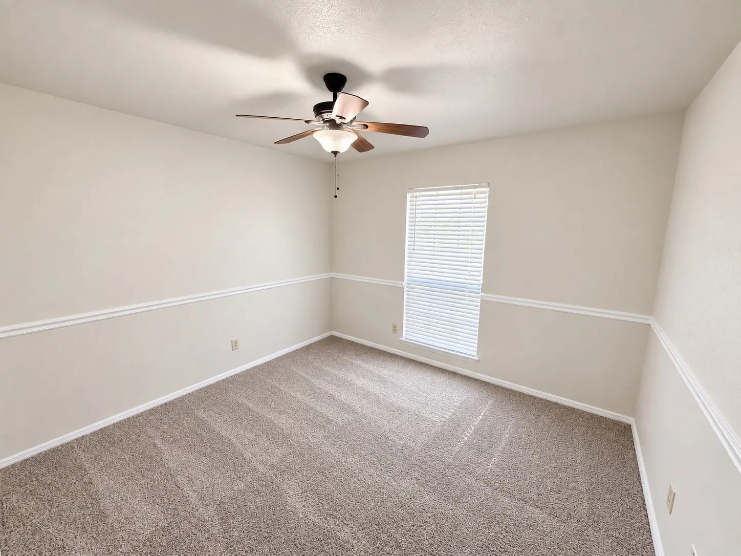 Neutral-toned carpeting, ceiling fan with integrated lighting, window with horizontal blinds, and decorative chair rail molding