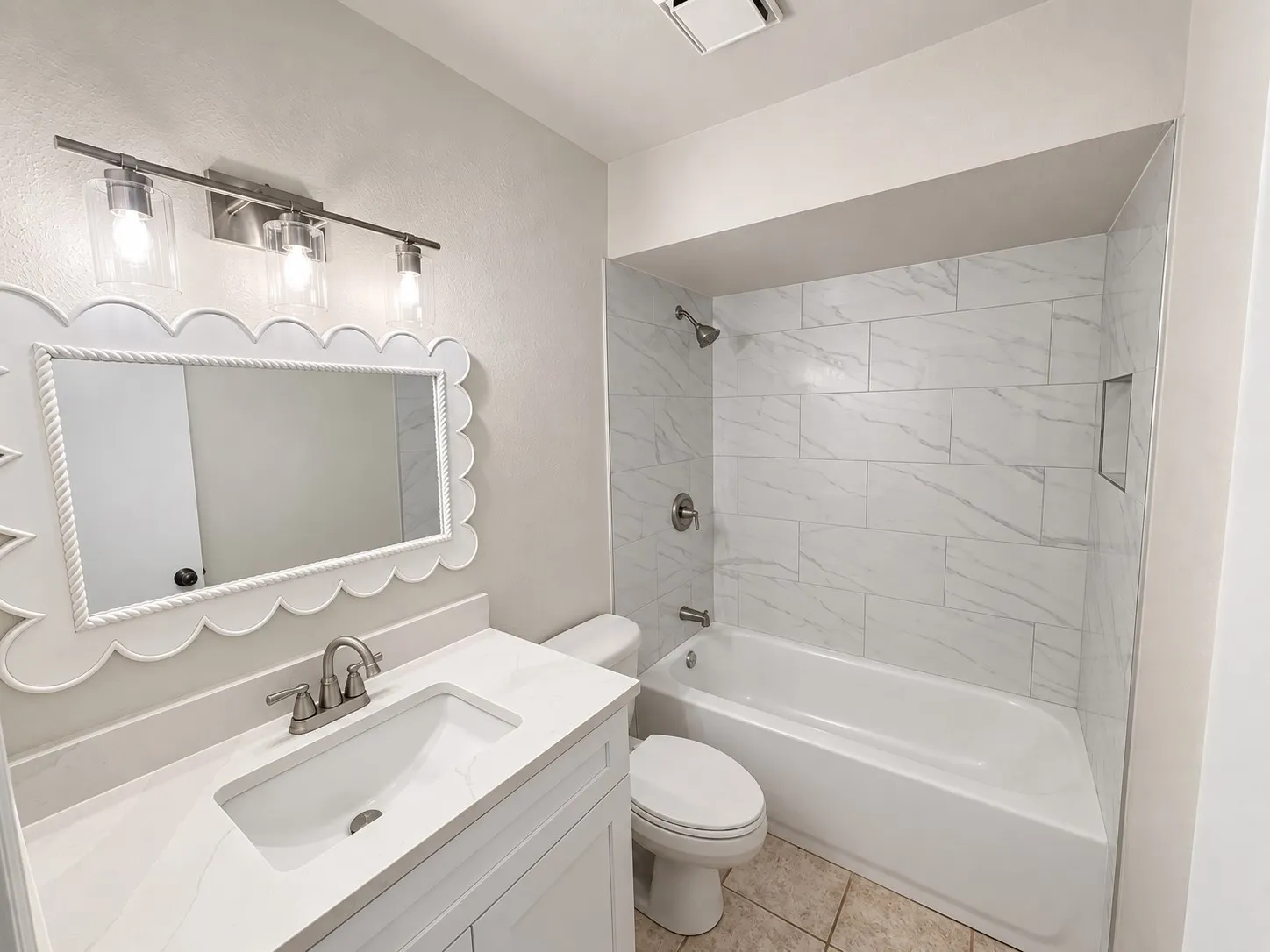 White vanity with an integrated sink and brushed nickel faucet, complete with a contemporary three-light fixture
