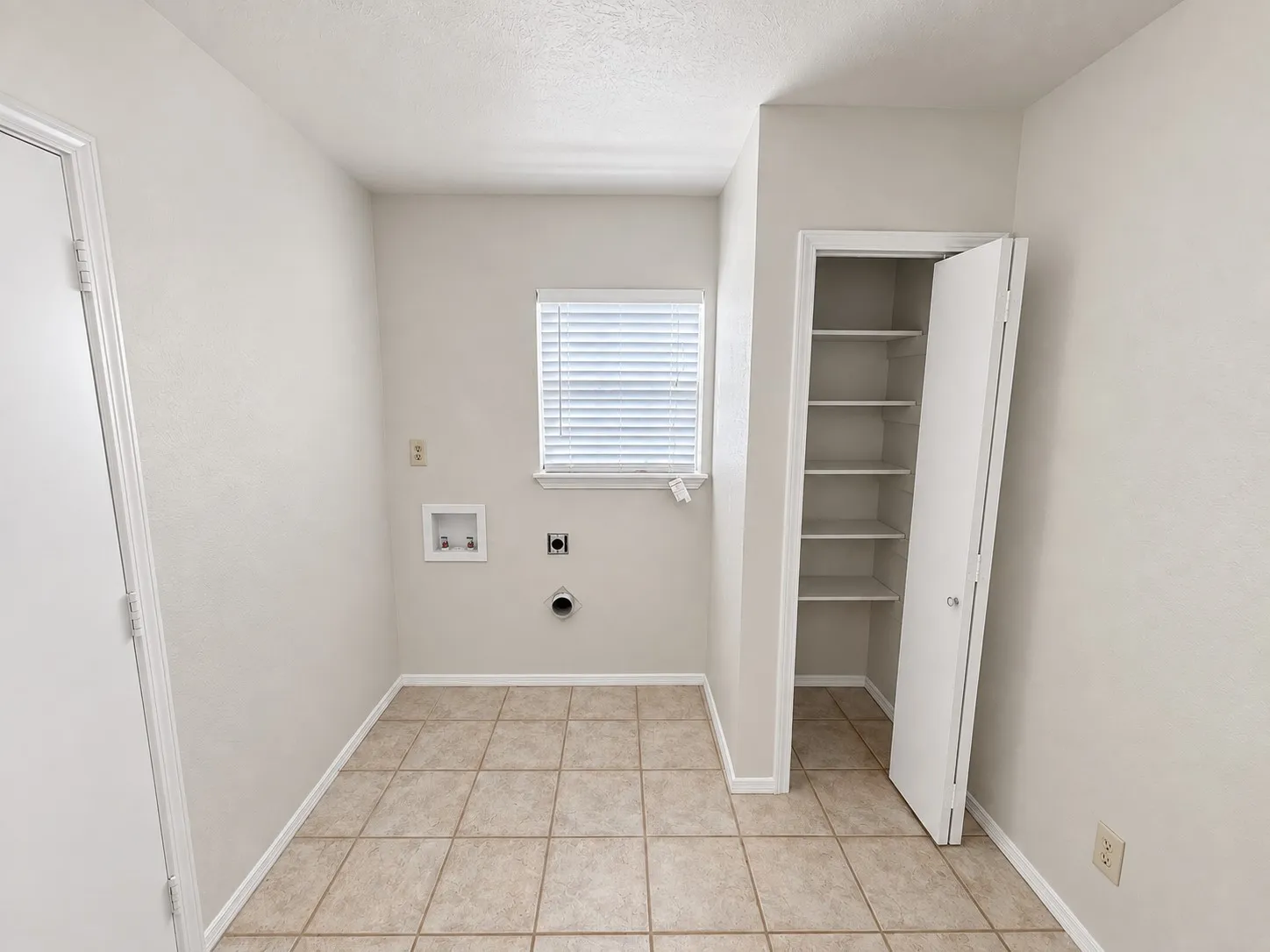 Laundry area with tile flooring, window with blinds, and built-in shelving