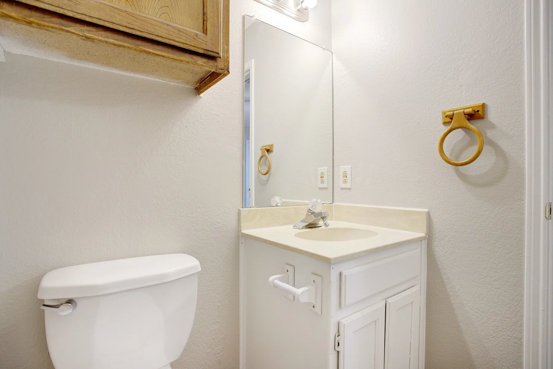White vanity with a built-in sink, wall-mounted mirror, and overhead lighting
