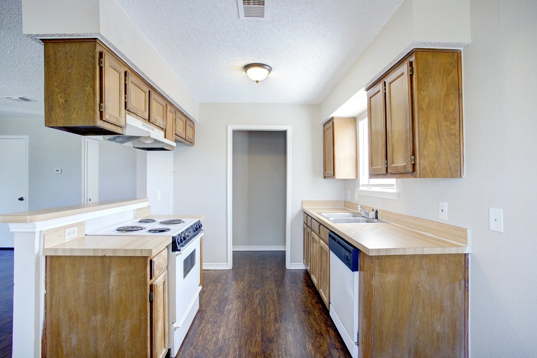 Kitchen featuring wood-finish cabinetry, a freestanding range, and a dishwasher