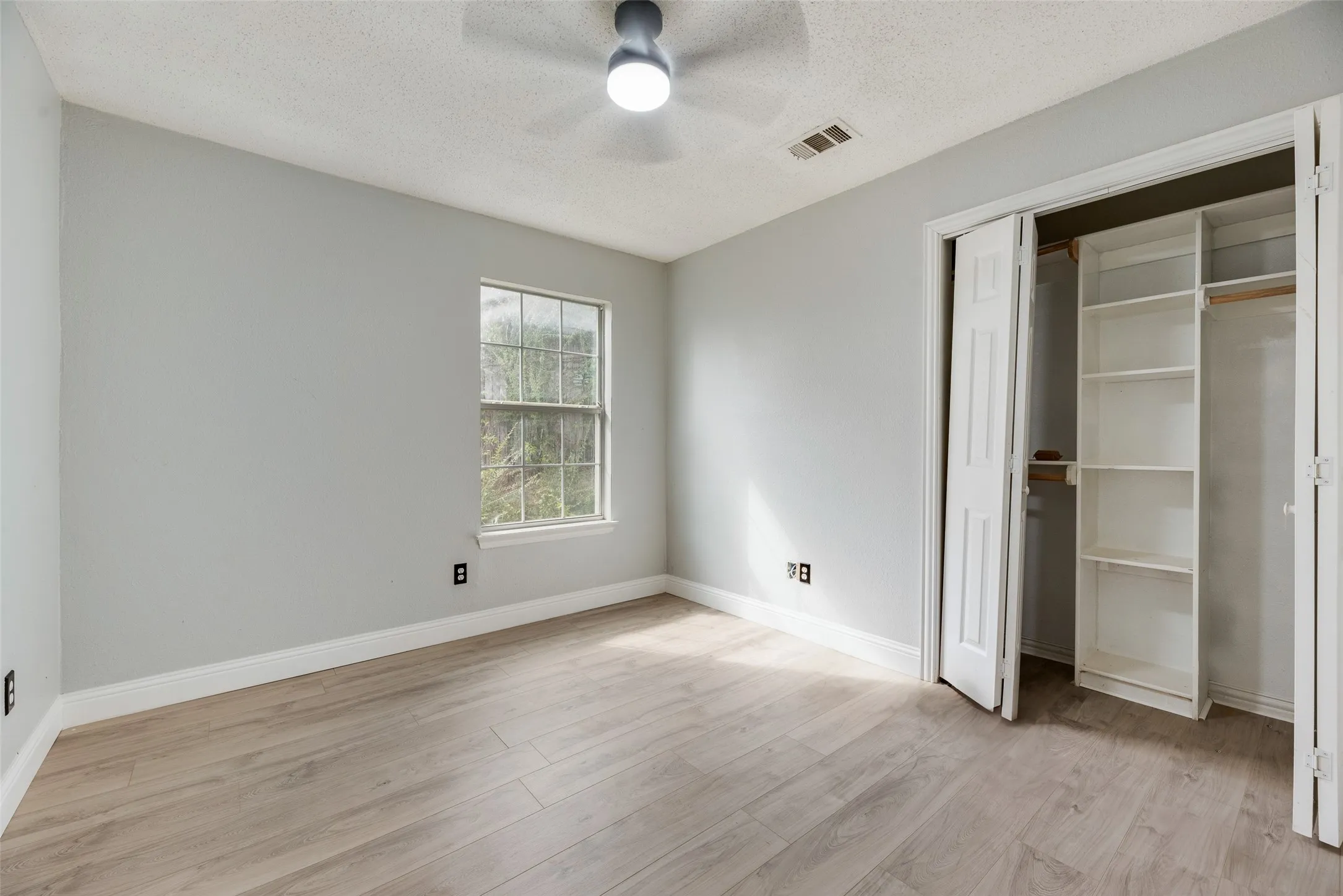 Wood-finish flooring, ceiling fan, bi-fold closet doors, built-in closet shelving, and a double-hung window